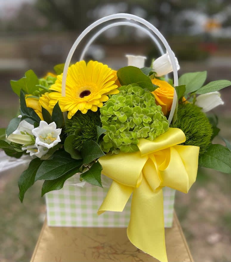 The Checkmate - The Checkmate – Cheerful Flower Arrangement | Wilmington, Delaware Florist Make a bold and joyful statement with The Checkmate, a playful floral arrangement handcrafted by your trusted local florist in Wilmington, Delaware. This fresh, vibrant design features lush green hydrangea, textured green dianthus, sunny yellow gerbera daisies, and classic yellow roses, artfully arranged in a cute checkered cardboard purse. Finished with a bright yellow satin ribbon, The Checkmate is a fun and uplifting gift that’s sure to bring smiles. Perfect for birthdays, thank-you gifts, get-well wishes, or just because, The Checkmate is available for flower delivery in Wilmington, DE and nearby areas including Chadds Ford, Kennett Square, and Newark. Each arrangement is made with premium, fresh flowers and offered with local hand delivery, making it a unique and cheerful choice for any occasion. Tax free, same day hand delivery.  