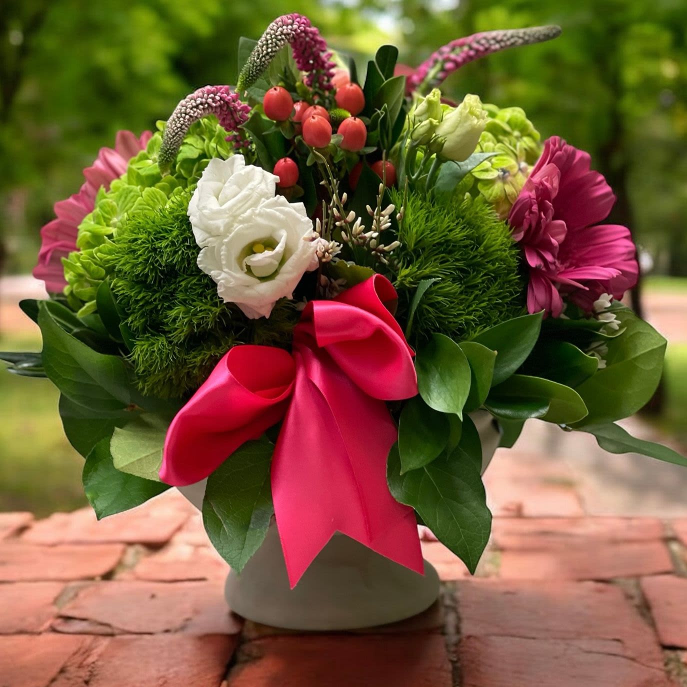 Wild About You! - Wild About You – Lush Pink and Green Floral Arrangement | Wilmington, DE Local Florist  Show your passion with Wild About You, a vibrant and romantic floral arrangement designed by Petals Flowers and Fine Gifts, your go-to local florist in Wilmington, Delaware. This stunning design features lush green hydrangea, bold dark pink gerber daisies, elegant white lisianthus, eye-catching dark pink veronica, and delicate pink hypericum berries. Artfully arranged in a charming stone pedestal container and finished with a rich dark pink satin ribbon, Wild About You is perfect for anniversaries, birthdays, or any occasion where you want to make someone feel truly special.  We proudly provide same-day flower delivery in Wilmington, DE, and to nearby areas including Hockessin, Newark, Glen Mills, Chadds Ford, Christiana, and Kennett Square.  Why Choose Us:  * Locally owned and operated florist deeply connected to the Wilmington, Delaware community * Premium, hand-crafted floral arrangements made with care and creativity * Commitment to exceptional customer service and a 100% satisfaction guarantee * Tax-free flower delivery on all orders Order Wild About You today from Petals Flowers and Fine Gifts and surprise someone with a gift that’s as unforgettable as they are!