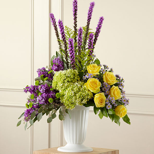 The FTD Affection Arrangement - Contrasting blooms of purple green and yellow create an original and beautiful expression of sympathy and sorrow eminently appropriate for celebrating a life that has passed. This stately arrangement handcrafted by a local FTD artisan florist features an eye catching silhouette of purple liatris stretching heavenward surrounded by yellow roses purple stock lavender Monte Casinos and green hydrangea and button poms in a pedestal urn with the look of fine white ceramic. This “statement bouquet” makes a welcome addition to a wake funeral or graveside burial service.