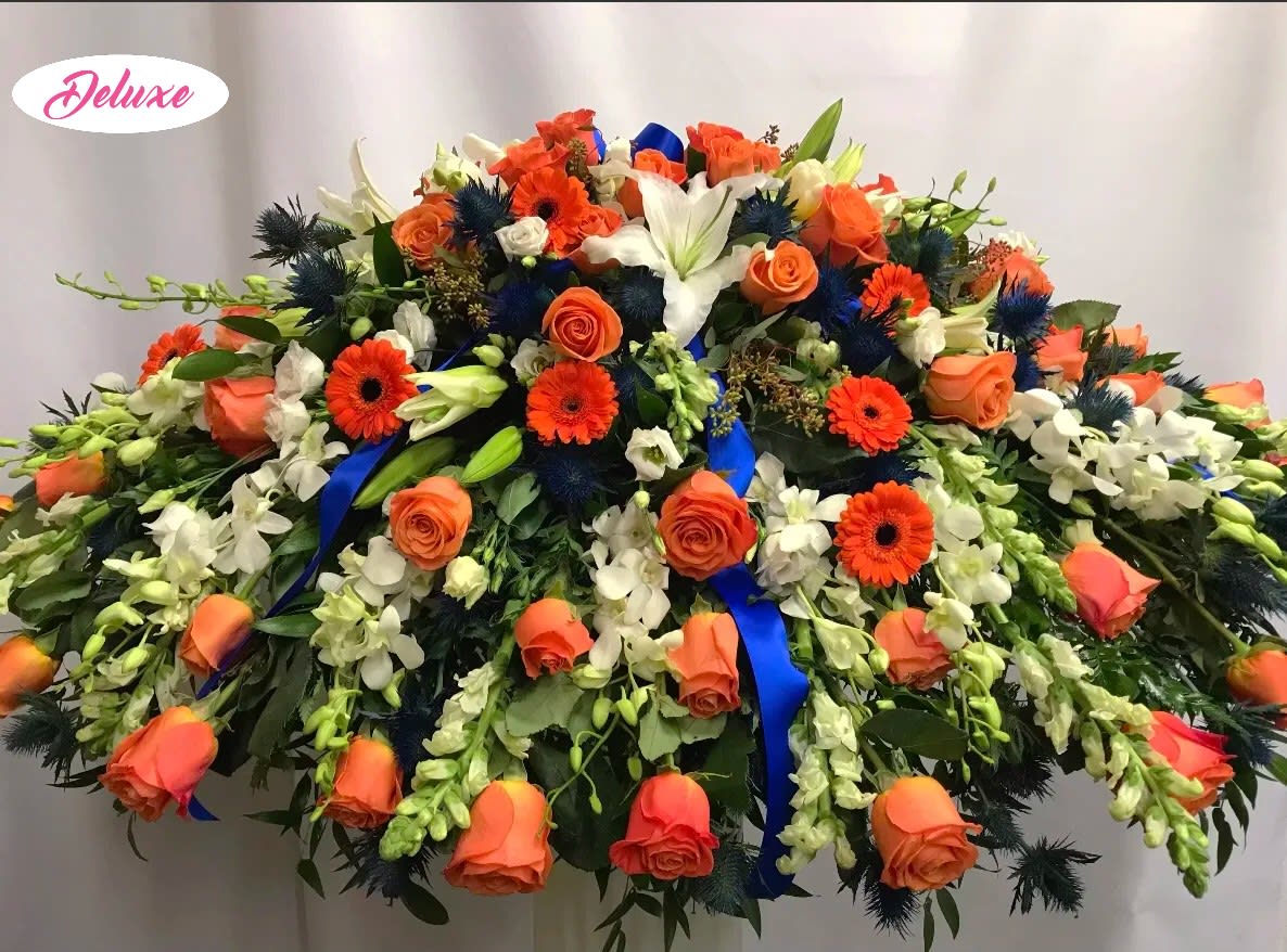 Lasting Memories Casket Cover - A beautiful assortment of bright orange Roses, Gerber Daisys and vibrant blue Delphinium are complimented by white Lilies, Orchids, Snap Dragons and other seasonal flowers. 