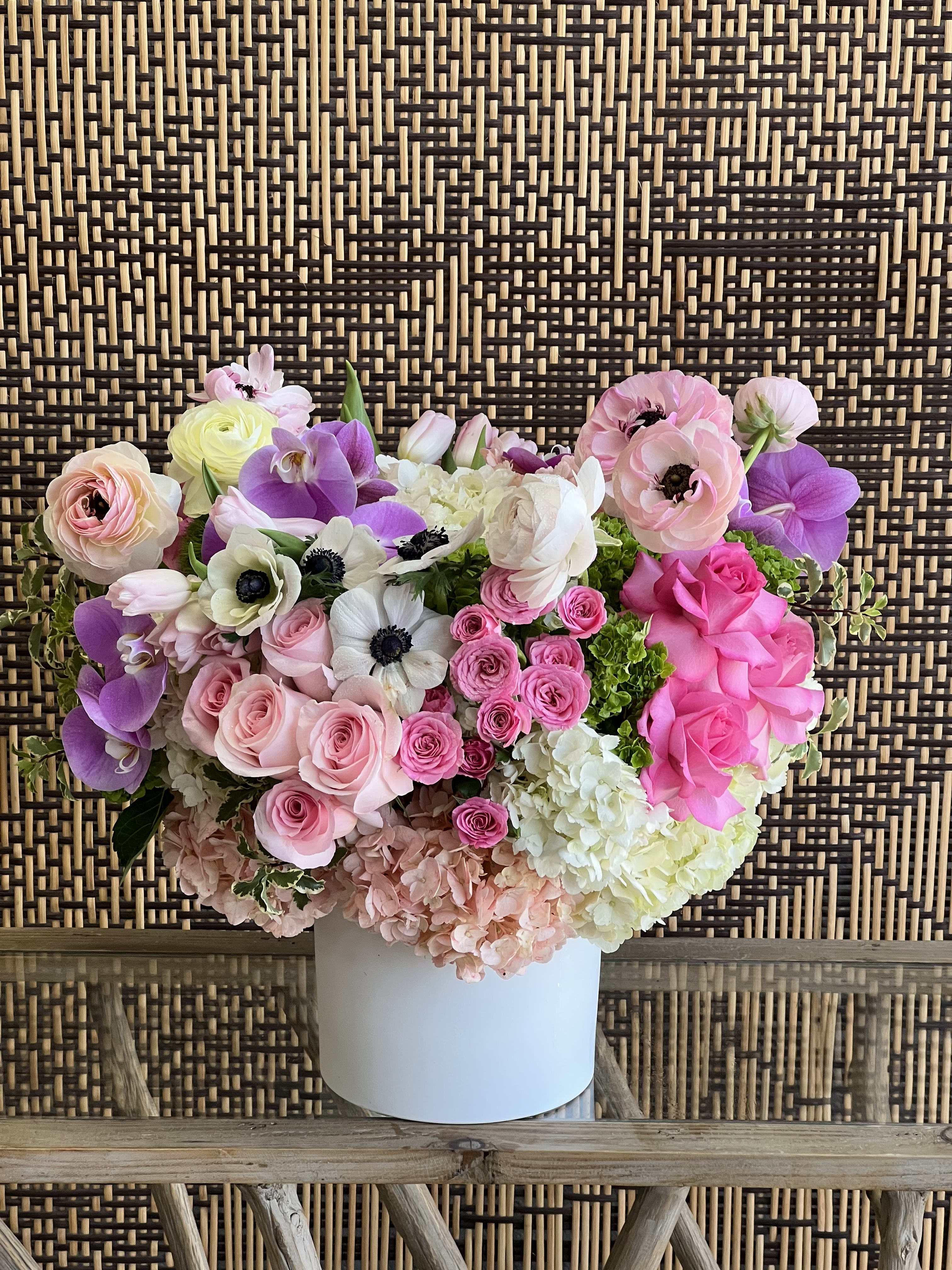 Petite Pink - A simple, sweet arrangement of Roses, Spray Roses, Anemones, Tulips, Ranunculus and Hydrangea, finished with purple Phalaenopsis Orchids, in a white ceramic vase