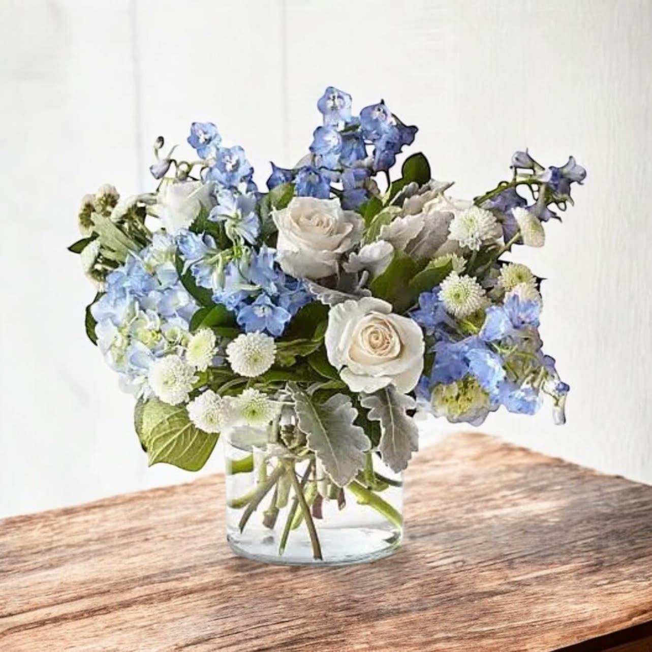 Mon Cheri - Mon Cheri – Elegant Blue and White Flower Arrangement | Wilmington, Delaware Local Florist  Simple yet striking, Mon Cheri is a beautiful floral design handcrafted by your Wilmington, Delaware florist. This elegant arrangement features graceful blue delphinium paired with classic white roses, thoughtfully arranged in a clear glass cylinder vase for a clean, timeless look. Perfect for birthdays, anniversaries, sympathy, or to brighten any room with its serene beauty.  Order Mon Cheri today for same-day flower delivery in Wilmington, DE and surrounding areas. Trust our local flower shop for fresh, premium blooms and outstanding service.