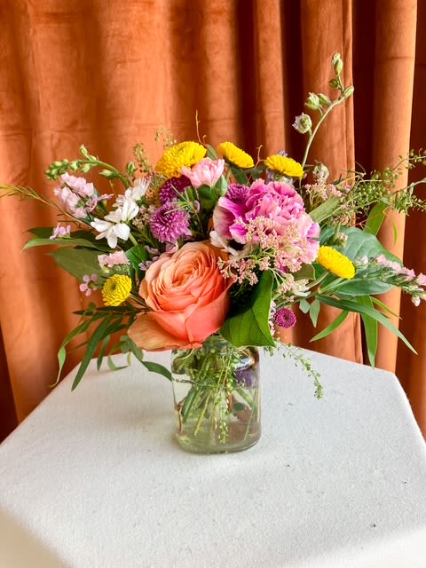 First Bloom - First Bloom is a designer's choice arrangement that captures the untamed beauty of a wildflower field. Featuring seasonal blooms in vibrant cheerful tones, each design is one-of-a-kind - perfect for brightening someone's day or celebrating life's joyful moments. While specific flowers may vary with the season, the lively spirit and radiant palette will always shine through.