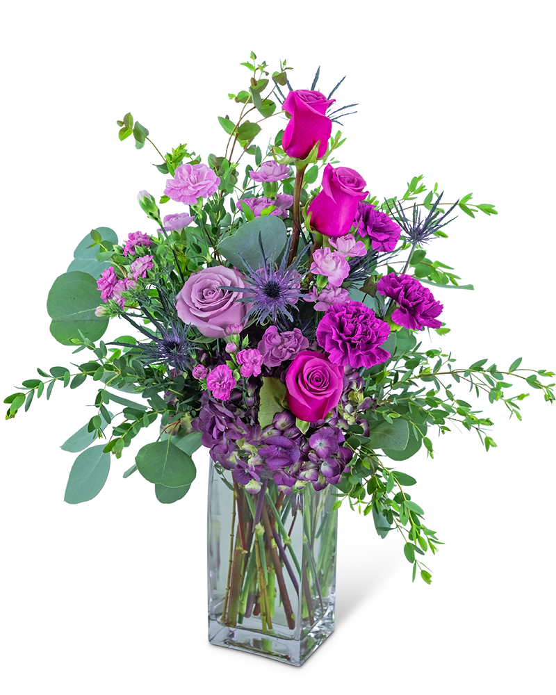 Tall arrangement of purple and hot pink roses and carnations in a clear glass vase