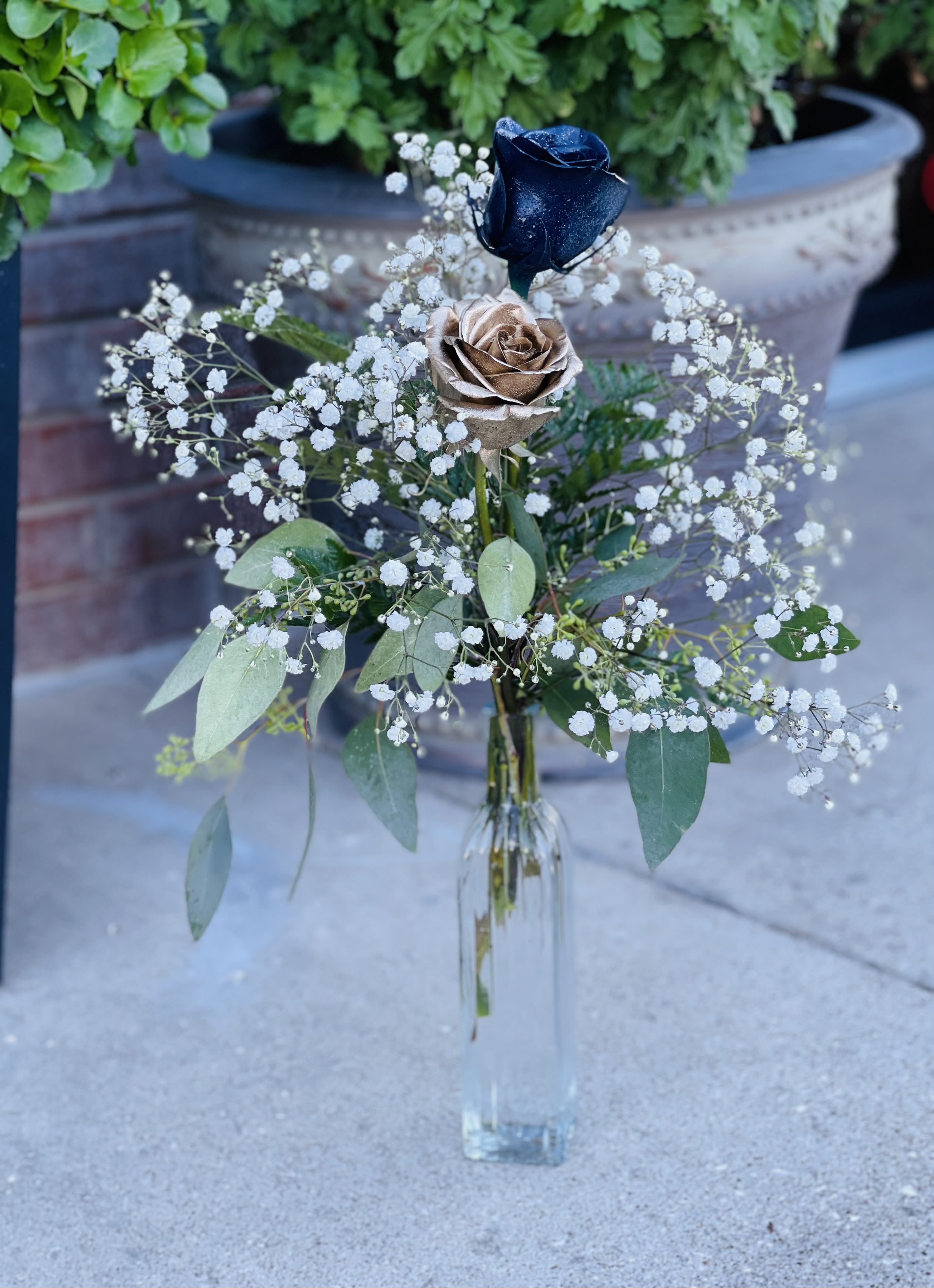 Royal Gleam - In store pick up only!    Royal Gleam A single gold rose and a single navy blue rose come together in a tiny vase, accented with soft baby’s breath for a gentle, airy touch. Simple, elegant, and eye-catching, this arrangement adds a hint of charm and a pop of color to any space.