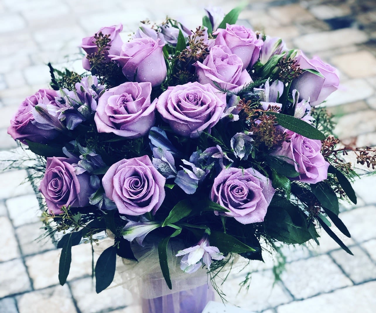 Dozen Purple Rose Bouquet - Dozen Purple Rose Bouquet Bold, elegant, and truly enchanting, this stunning bouquet features twelve luxurious purple roses accented with fresh greenery. Purple roses symbolize admiration, mystery, and love at first sight, making this arrangement a captivating way to express deep affection and admiration. Handcrafted with care and beautifully wrapped, this bouquet is perfect for anniversaries, birthdays, or making a statement that’s unforgettable and full of charm.