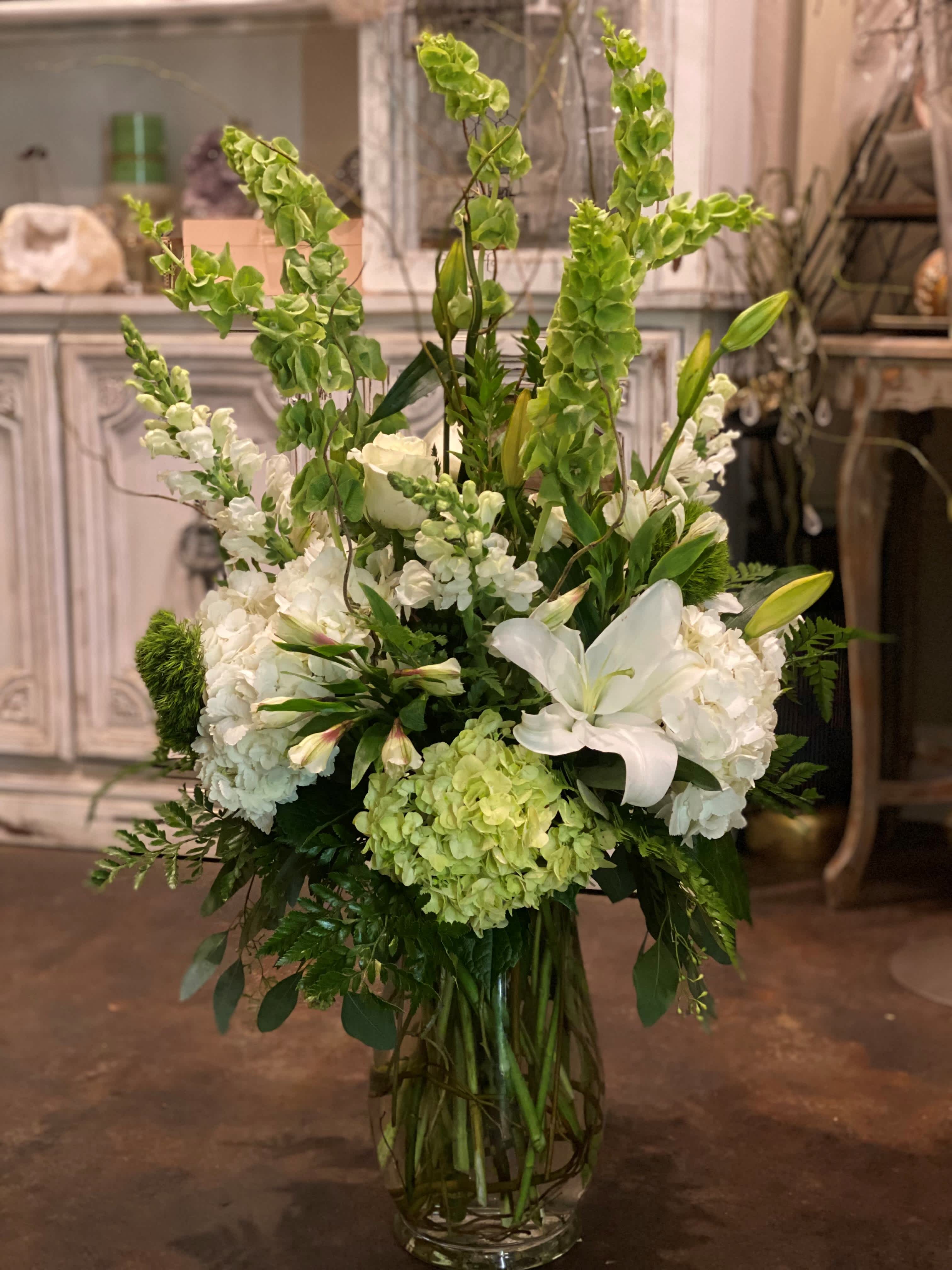 Serene Green  - A fresh mix of white green  hydrangeas, bells of Ireland, white snapdragons, white roses, white lilies, other mixed greens, designed to create unforgettable memories with a serene look. 