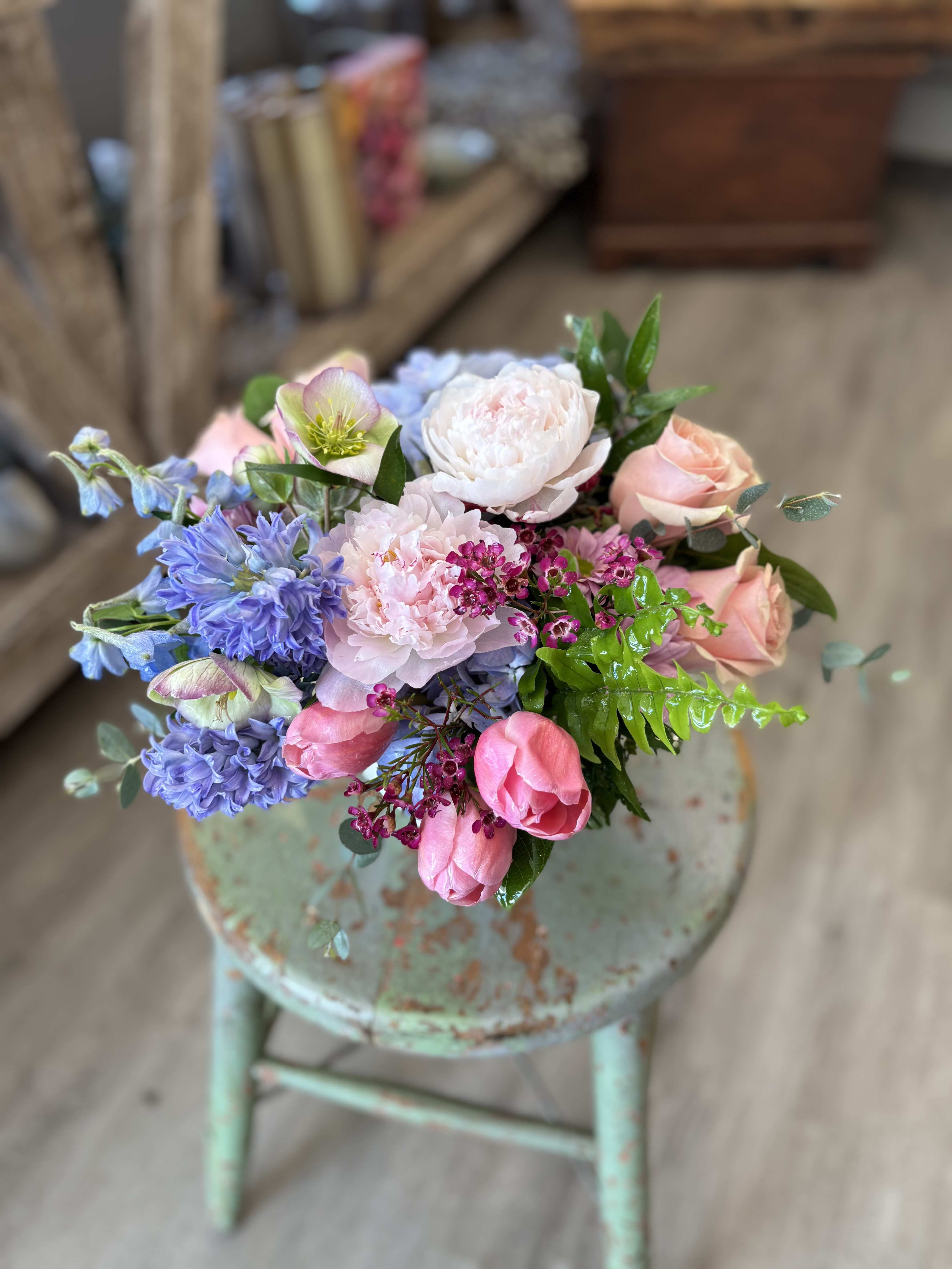 Spring Embrace  - A soft, garden-style arrangement gathered in fresh spring tones. Hydrangea, fragrant hyacinths and delicate roses are layered with airy accents in our fluted white ceramic container. Perfect for celebrating any loved one. 