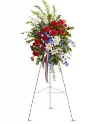 Patriotic Tribute Standing Spray - A modern and striking standing spray designed to honor and celebrate a life with dignity and pride. This patriotic arrangement features an elegant blend of white lilies, vibrant red carnations, and red mini carnations, complemented by either white snapdragons or stock for added height and texture. Accents of rich blue delphinium bring a bold touch of color, beautifully balanced with lush fresh greens. Finished with a tri-color red, white, and blue sympathy bow, this design creates a meaningful and respectful tribute with a contemporary style.