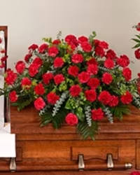 Timeless Tribute - A simple yet dignified casket spray featuring rich red carnations artfully arranged with a lush mix of fresh greens. The compact, classic design offers a heartfelt and respectful tribute, emphasizing elegance and timeless beauty.