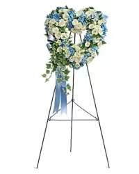 Tender Tribute Spray - A tender and heartfelt open-heart spray, thoughtfully designed as a sympathy tribute for a child. This 12–15 inch arrangement features soft white spray roses and serene blue hydrangeas, accented with fresh greens for fullness and texture. A coordinating blue bow completes the design, creating a gentle, comforting, and visually soothing expression of love and remembrance.