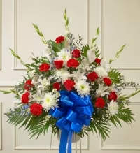 Graceful Tribute Arrangement - A classic fan-shaped sympathy arrangement, thoughtfully designed to express heartfelt remembrance. This elegant display features a harmonious mix of chrysanthemums, carnations, and roses, accented with lush fresh greens for fullness. A coordinating blue bow adds a tasteful touch of color, creating a polished and respectful tribute. Available in small, medium, and large sizes, this arrangement can be customized to suit any space or setting.