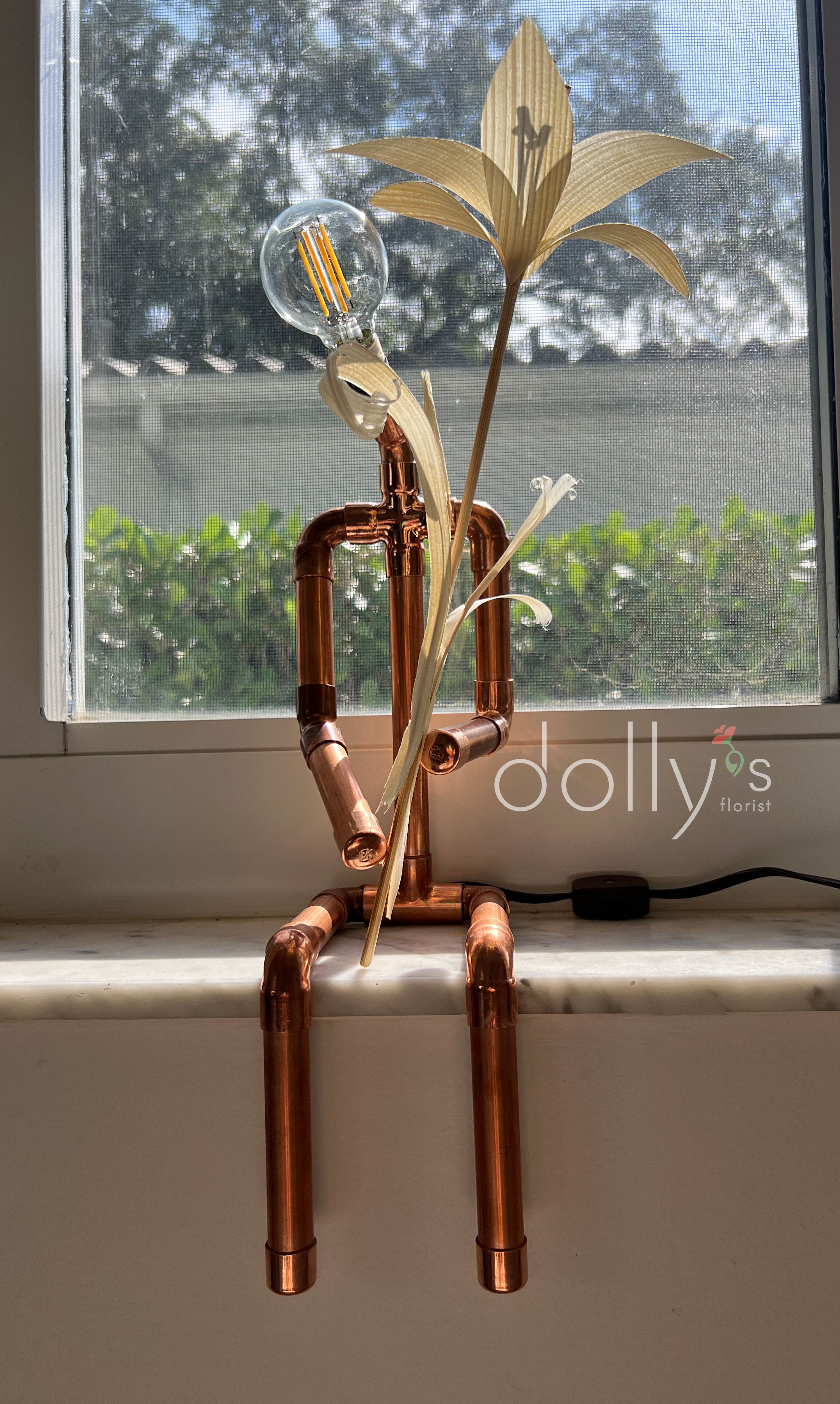 Copper pipe figure with a light bulb head and palm-like leaves