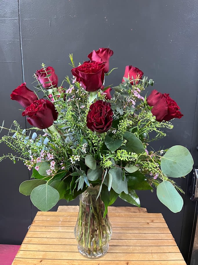 Classically Designed Red Roses - An all around flower arrangement designed with fresh flowers to include 1 dozen red roses, filler, and mixed greens in a vase.   * Some stages of flower life may vary. (Example: Lilies may be more open than imaged.) Flower shortages and product availability means that some substitutions will apply. Value will always be filled. This bouquet might include eucalyptus amongst the greenery. It may be toxic to pets including but not limited to cats and dogs if digested.