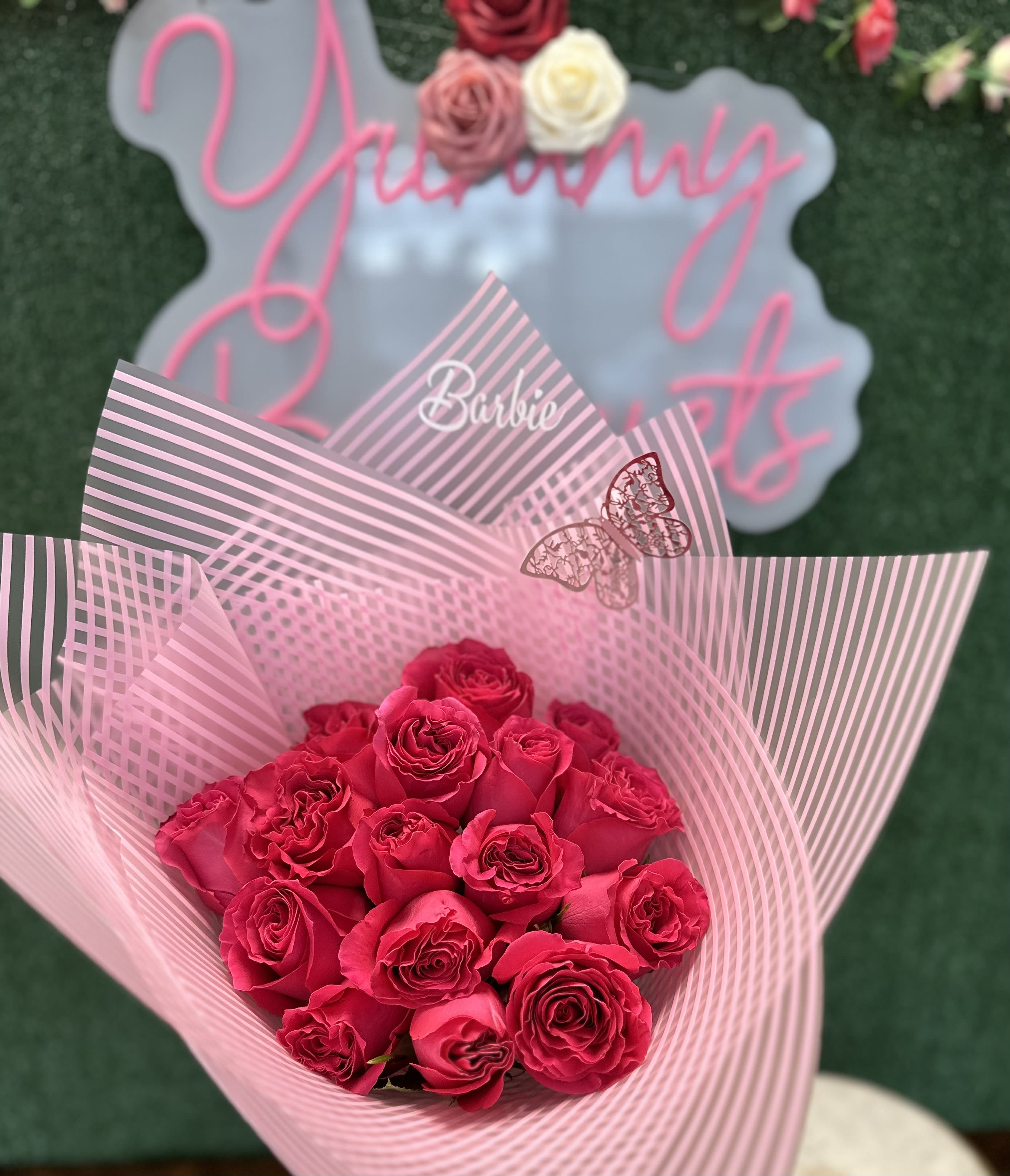 Barbie buchon - Fresh roses on pink wrapping paper  "Picture is a reference every arrangement would not be exactly the same. Flowers and color substitution may apply" 