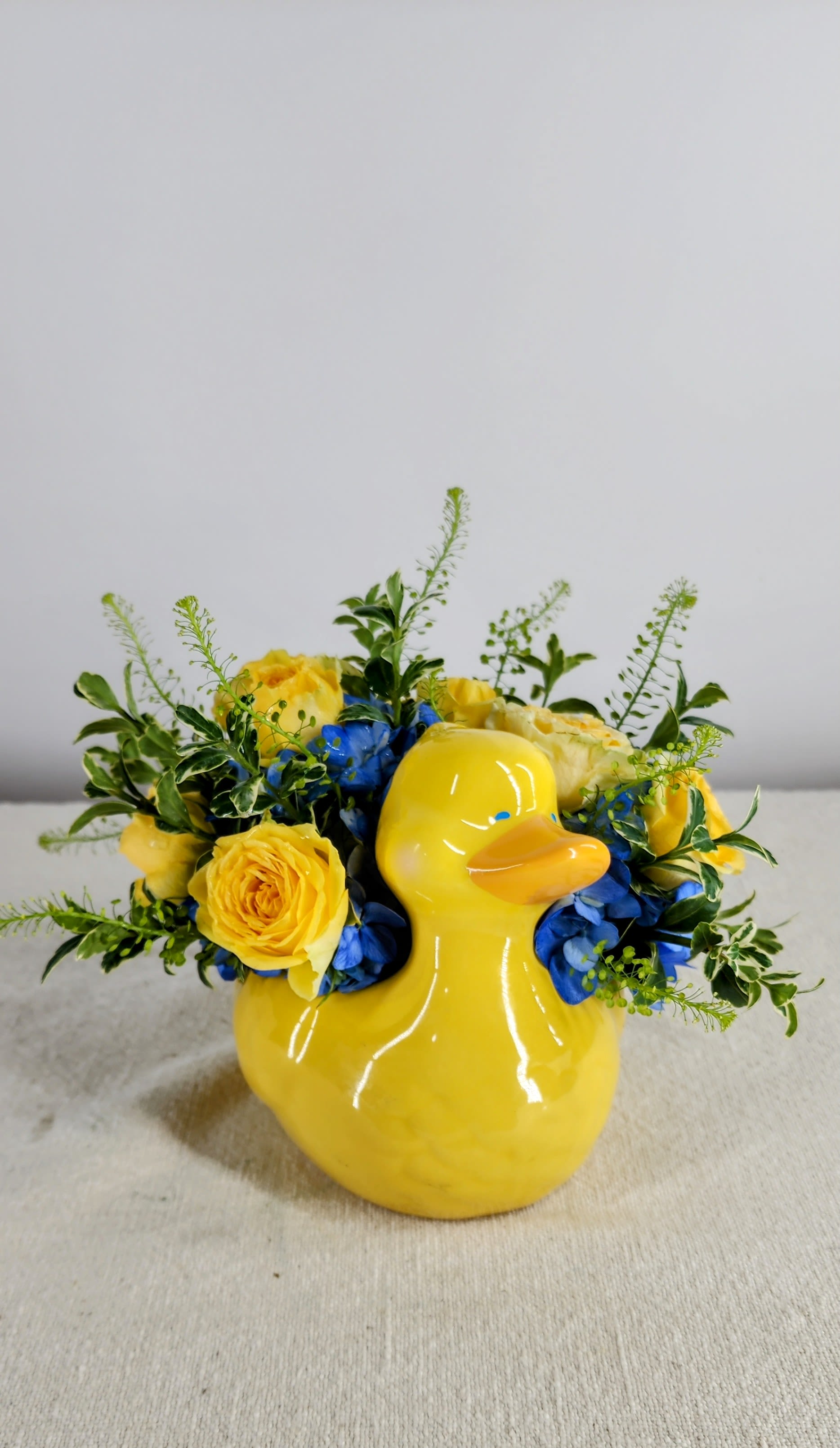 Baby Ducky - This adorable yellow ducky is filled with blue hydrangeas and yellow spray roses.  This cute arrangement is a perfect way to welcome a new baby into this world. ** This is also available with pink roses.