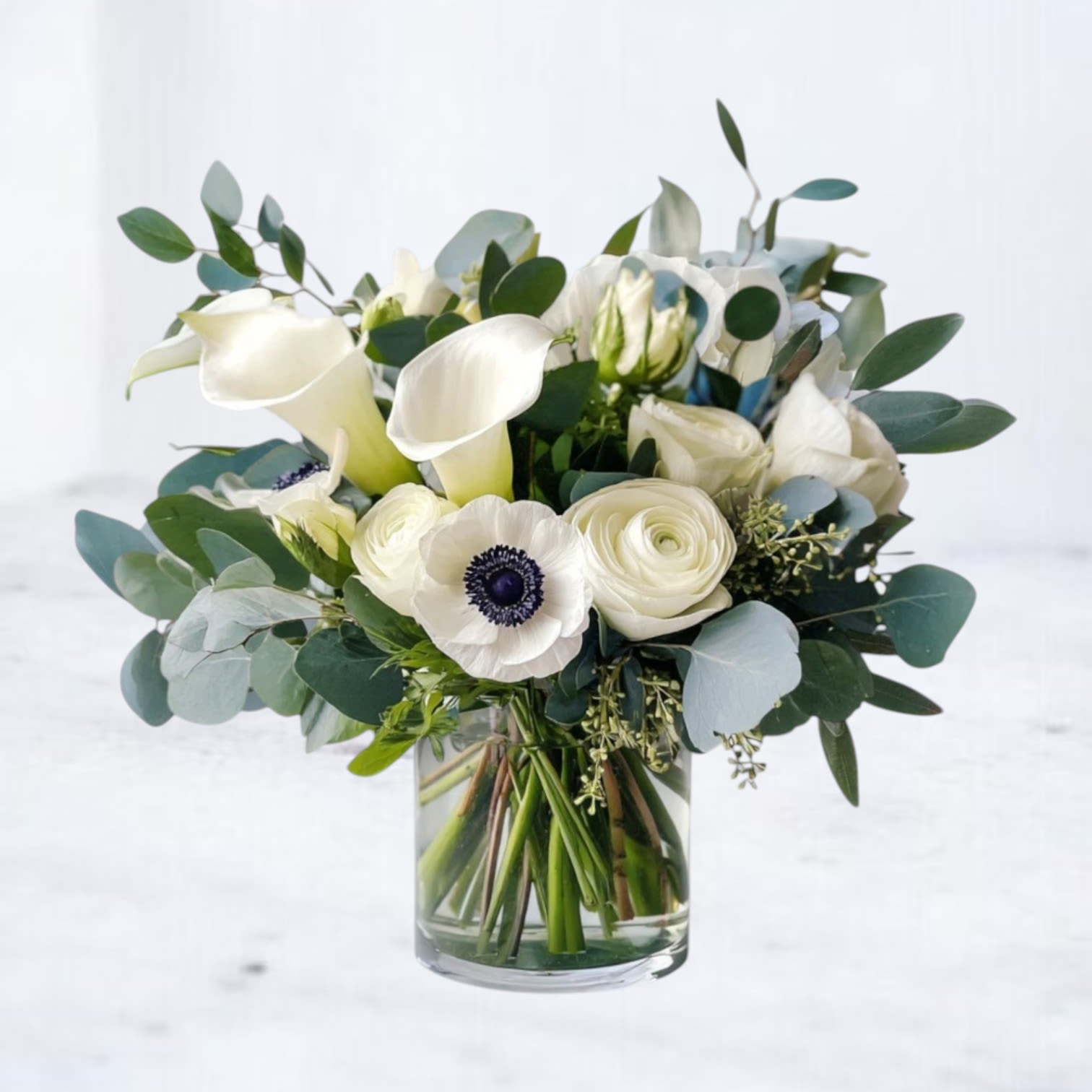 White Standard - White Standard features a clean mix of white roses, calla lilies, and seasonal blooms accented with fresh eucalyptus and greenery. Designed in a clear glass vase, this arrangement focuses on balance, texture, and a crisp, modern look. A dependable choice for sympathy, thoughtful gestures, or sending something simple and refined. Available for same-day flower delivery in Magnolia, Montgomery, The Woodlands, Conroe, and surrounding areas. Flower varieties may vary slightly while maintaining the overall style and color palette.