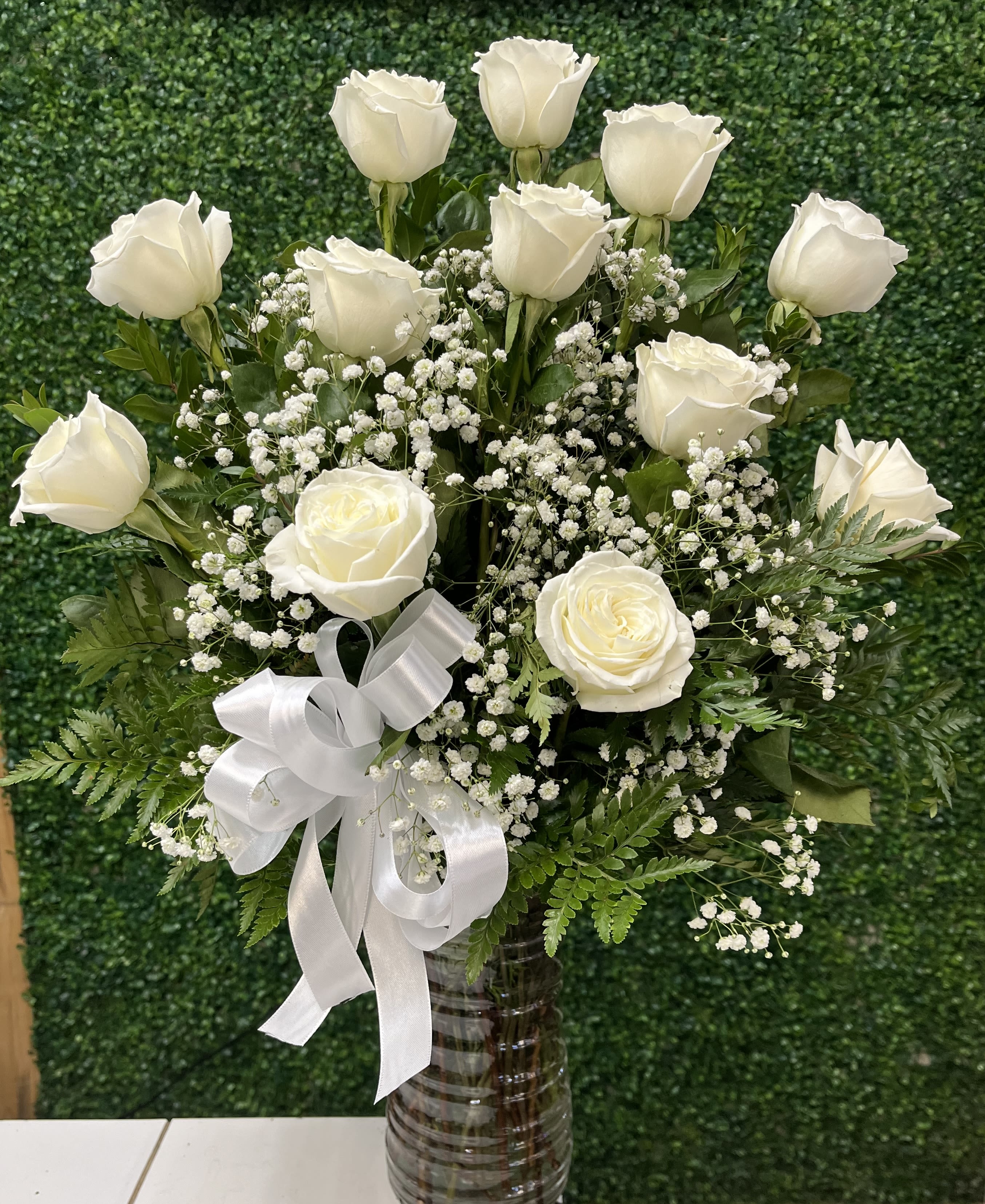 Dozen White Roses - Send them a lovely arrangment with 12 white roses. Perfect to send to someone you care deeply about. This arrangement is styles one face meaning that flowers are in front and greenery in back. 