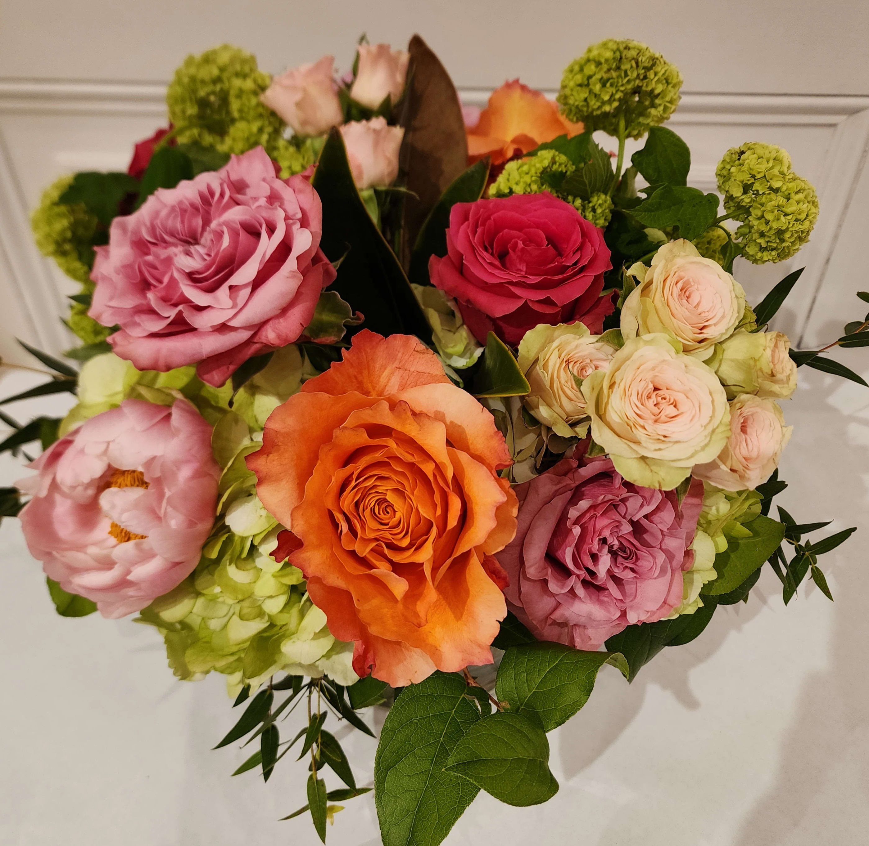 "Happiness Blooms" Bouquet - A background of assorted green flowers enhances the bright colors of this lovely arrangement. Hot pink roses, coral roses, pink spray roses and other premium blooms are sur to make any recipient giddy!
