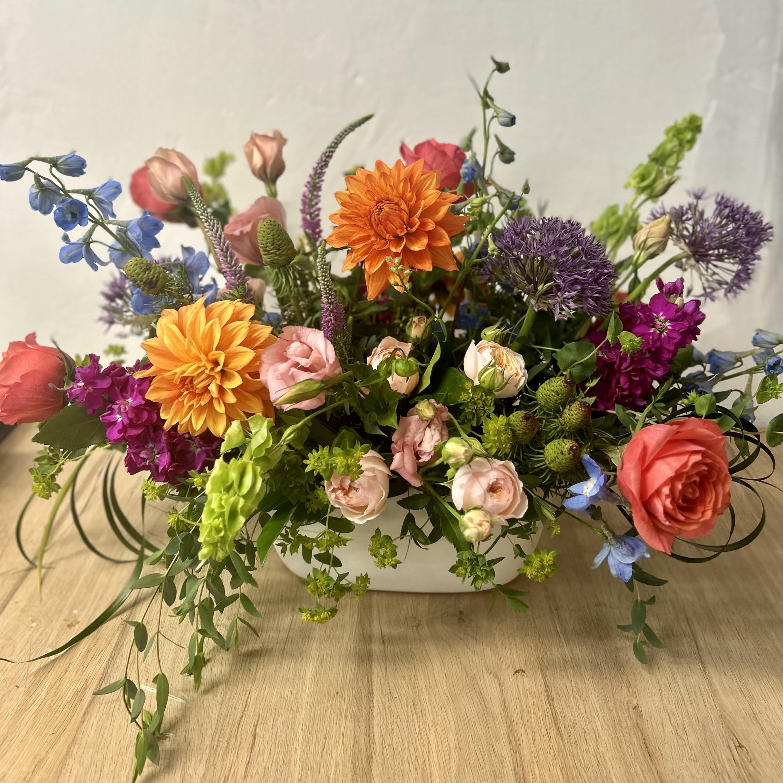 Summer Soiree  - A beautiful summer inspired arrangement, perfect to sit on any table. Made up of variety of seasonal flowers including dahlias, delphinium and roses. created in a white oval ceramic container. ***flowers and container are subject to substitution due to seasonal availability***