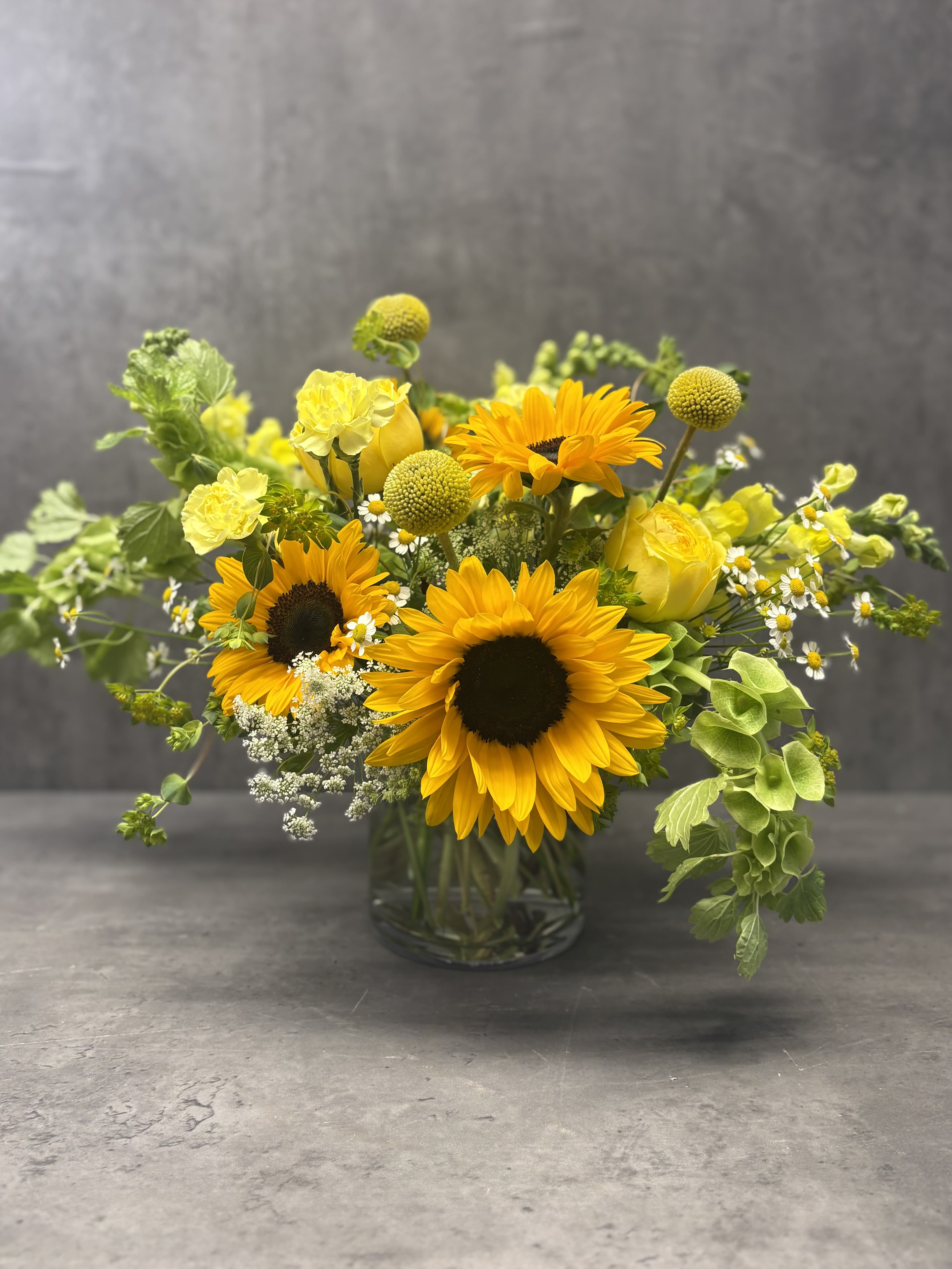Summertime Sunshine - A beautiful, seasonal mixture of cheerful yellow flowers featuring sunflowers. Created to bring sunshine to your loved one. 
