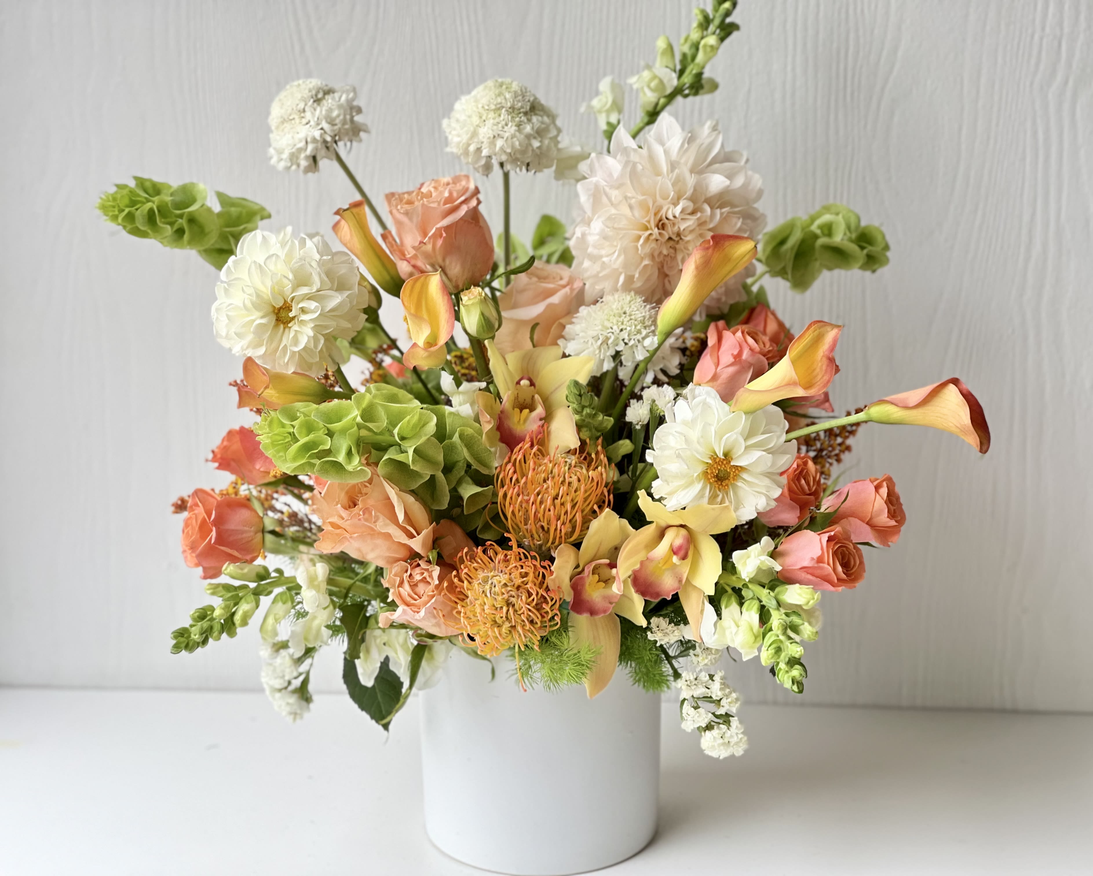 EC97 Peachy Perfection - Peachy Perfection – Soft Peach &amp; Cream Designer Floral Arrangement | Tustin Flower Delivery Bring warmth, charm, and elegance into any space with our Peachy Perfection arrangement — a thoughtfully curated blend of seasonal blooms in soft peach, apricot, cream, and green tones. This designer arrangement features a mix of premium roses, dahlias, calla lilies, pincushions, hydrangeas, snapdragons, and other fresh flowers arranged in a modern white ceramic vase. Peachy Perfection is ideal for birthdays, thank-you gifts, housewarmings, or simply as a stunning centerpiece to brighten a home or office. Its unique mix of textures and soft, warm colors gives it a garden-inspired, elevated look that works beautifully for any occasion. Same-day flower delivery available in Tustin, Irvine, Newport Beach, Costa Mesa, and nearby cities. 