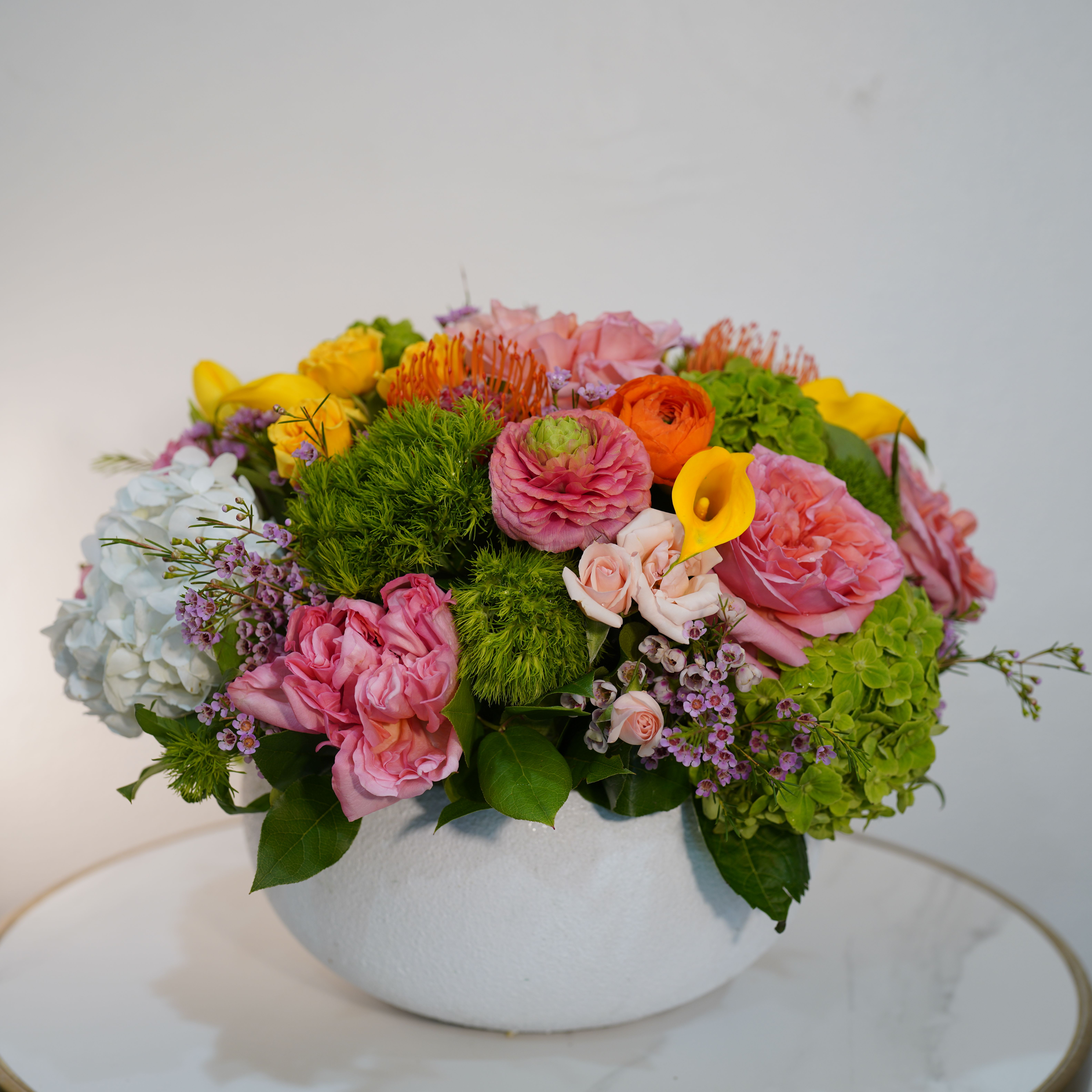 Vibrant Garden Bloom – Luxury Mixed Flower Arrangement - Celebrate color, beauty, and creativity with our Vibrant Garden Bloom, a luxurious mixed flower arrangement designed to make a statement. This stunning composition features a rich blend of premium seasonal flowers, including soft pinks, vibrant yellows, fresh greens, and delicate textures, all carefully arranged in a modern white ceramic bowl. The balance of colors and shapes creates a lively yet elegant design that instantly brightens any space. Perfect for birthdays, celebrations, or simply to impress, this arrangement brings energy and sophistication together in one unforgettable piece. Each design is handcrafted by Guy Floral Studio, ensuring a unique, fresh, and high-end presentation every time. Same-day flower delivery available in Beverly Hills, West Hollywood, Santa Monica, Beverly Grove, Bel Air, Culver City, and surrounding Los Angeles areas. 