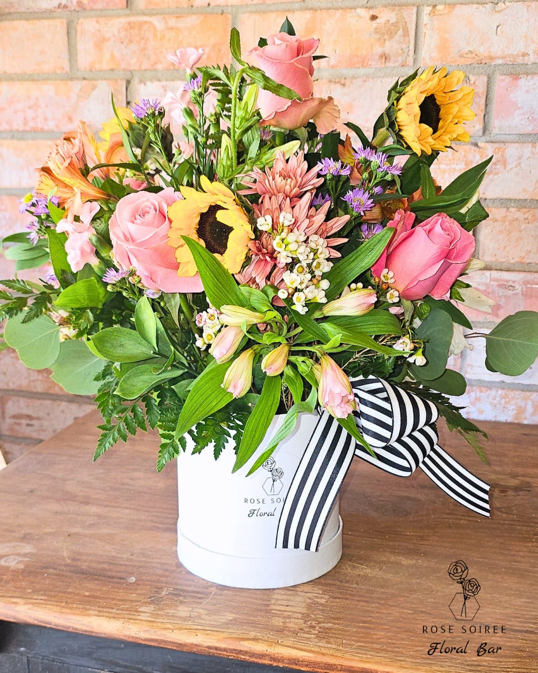 Sprung - Spring Mix - Sprung – Spring Mix is a designer’s choice arrangement featuring a lively blend of seasonal blooms in bright, uplifting colors. Designed to reflect the energy of spring, this piece brings a sense of renewal and joy to any space.  Perfect for celebrating new beginnings, birthdays, or simply adding a pop of color to someone’s day, this arrangement is both cheerful and effortlessly stylish.  Floral varieties may include tulips, roses, chrysanthemums, lilies, and seasonal accents. Specific blooms may vary based on availability while maintaining the overall color palette and design style.    Standard Box is approximately 5" x 5.5" Deluxe Box is approximately 6.5" x 6.5" Premium Box is approximately 7.25" x 7.25"