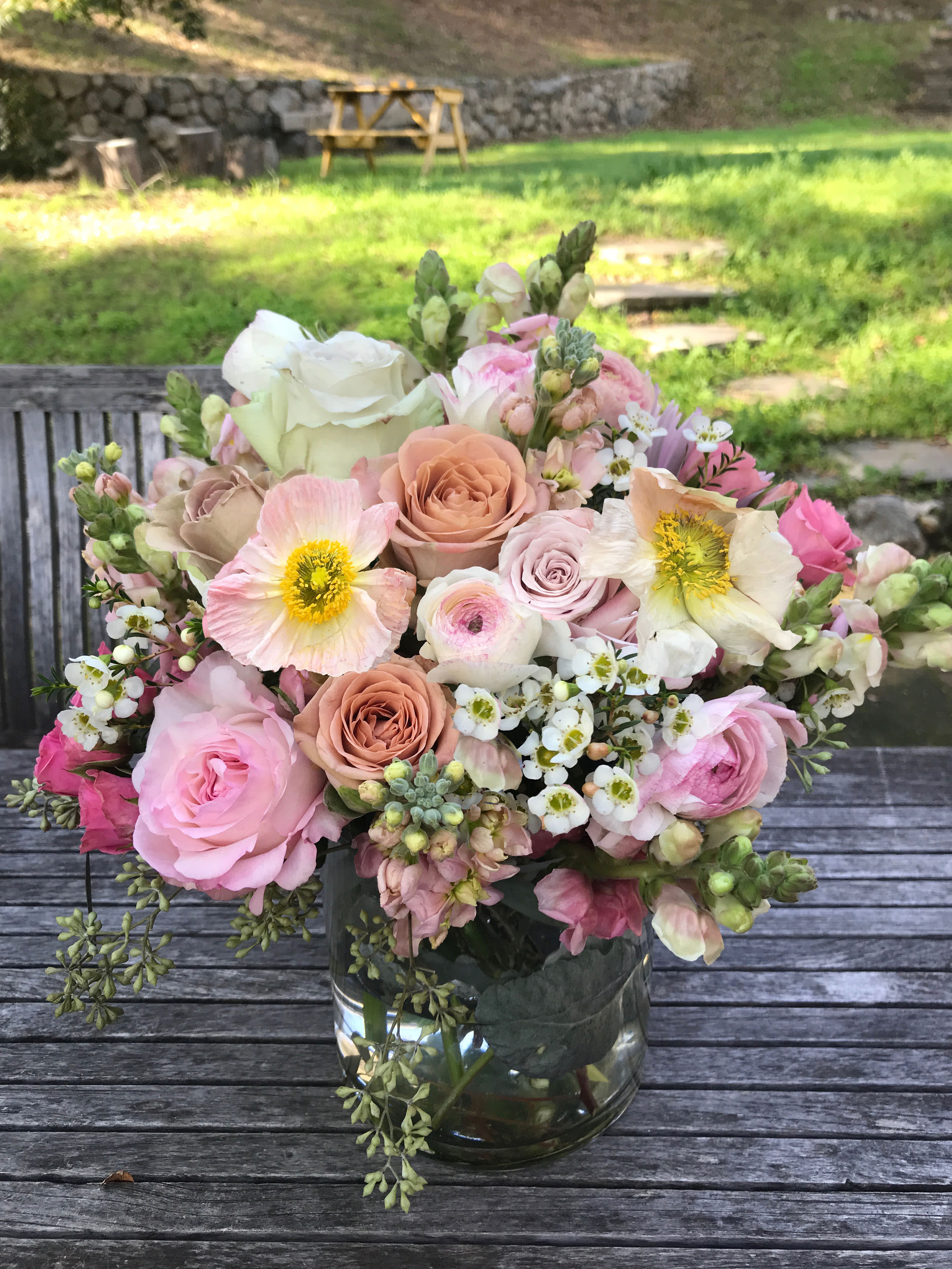 Melody arrangement - Natural and organic garden like arrangement of seasonal light pastel flowers, always containing roses and stock &amp; wax flowers. Poppies when in season, otherwise replaced with ranunculus Feminine and elegant perfect for the fashionable woman, for a day of romance, Valentine's Day or Mothers Day.