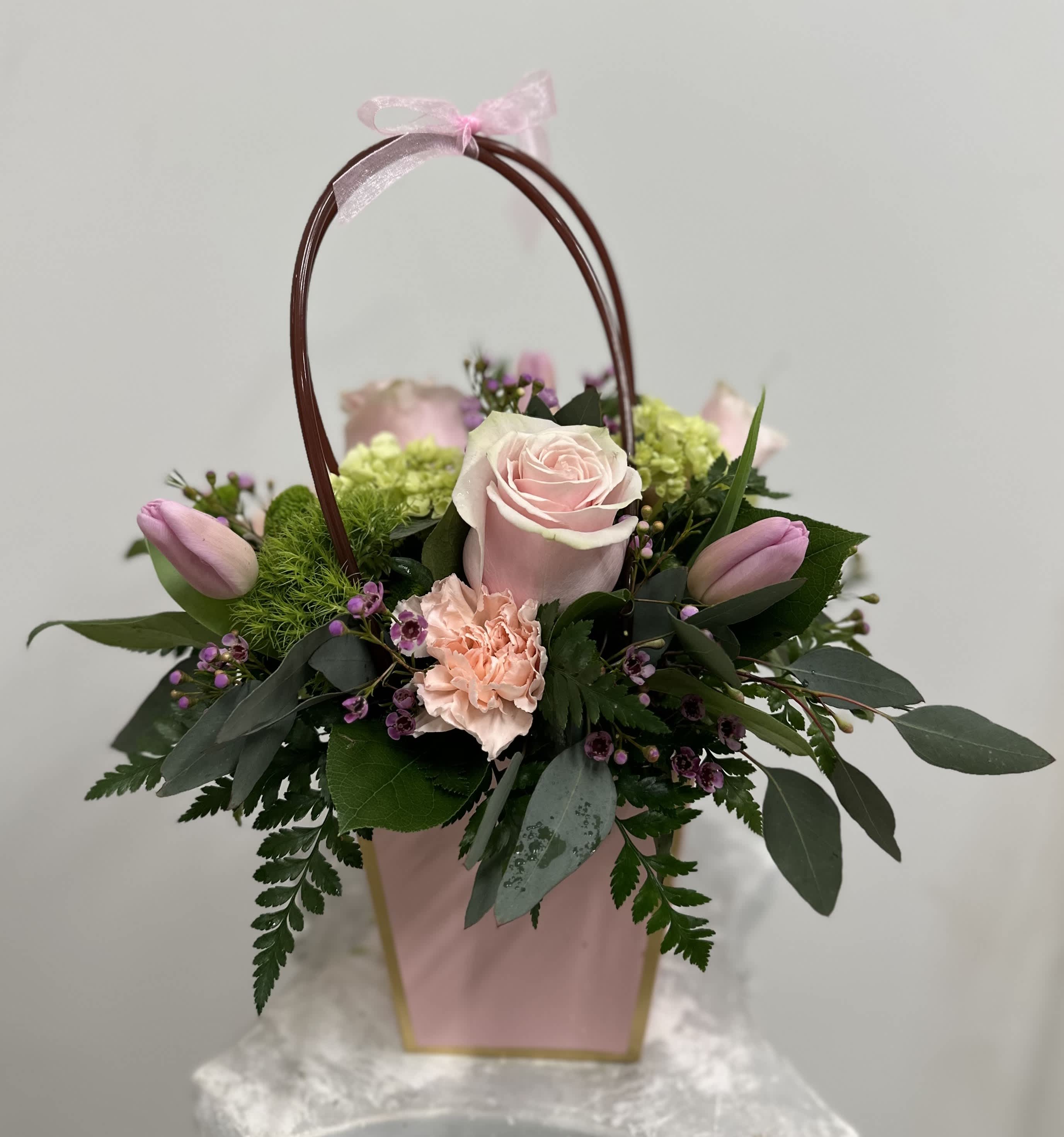 Blush Lady's purse by Westford Florist Art by Veny - Elevate your floral gift-giving with the Blush Lady's Purse by Westford Florist Art by Veny. This exquisite arrangement features a captivating blend of delicate pink roses, charming tulips, and whimsical wax flowers, beautifully complemented by vibrant green hydrangeas and soft peach carnations. Designed in a chic floral bag that exudes sophistication, this elegant ensemble is perfect for celebrating special occasions or adding a touch of grace to everyday moments. Delight someone special with this stunning expression of artistry and nature combined—a true testament to refined taste and thoughtful gifting.
