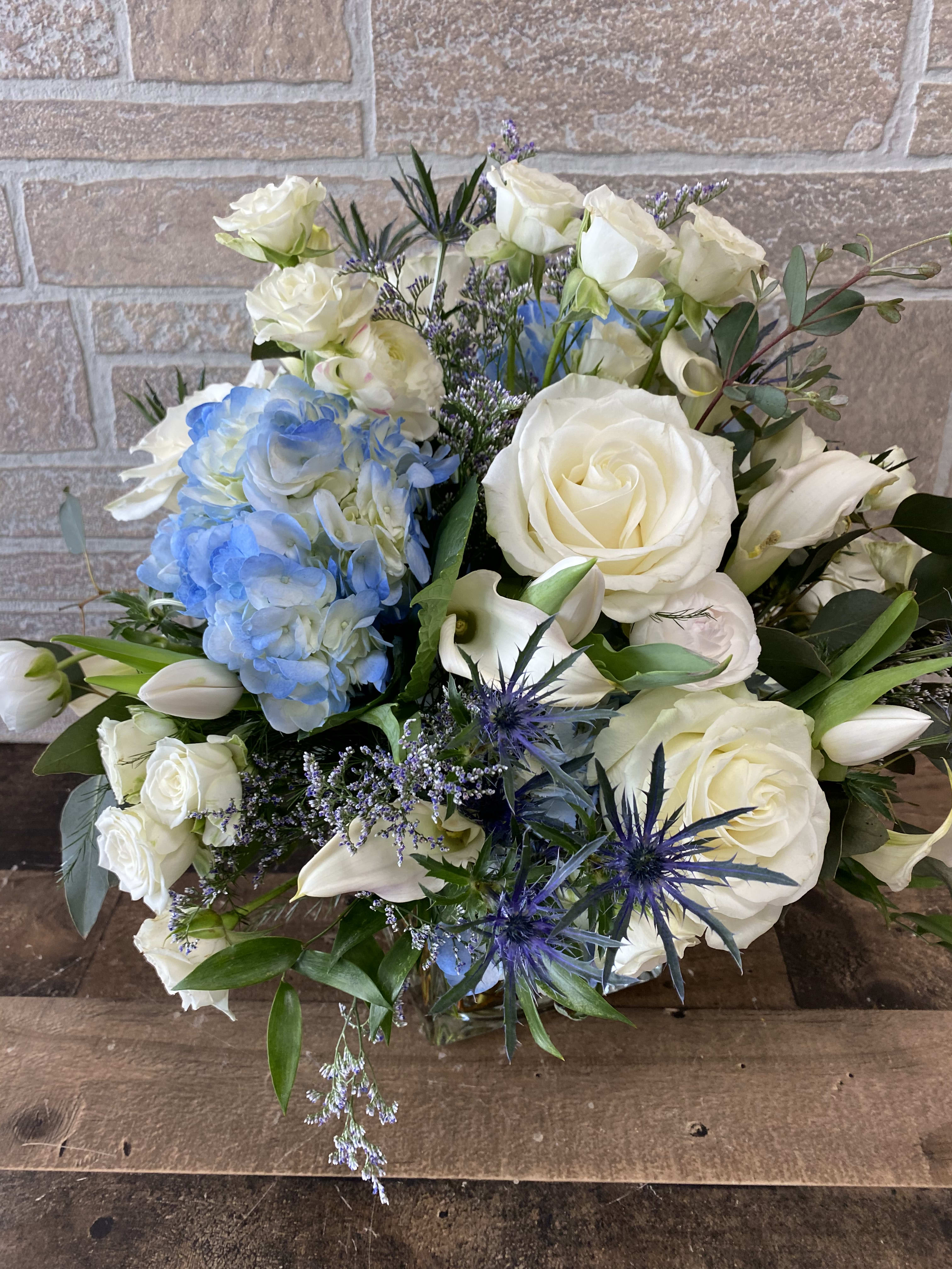 Audrey's Delight - Who says flowers don't come in Blue? Blue Hydrangea, Blue Thistle and White Roses in a cute little glass cube.