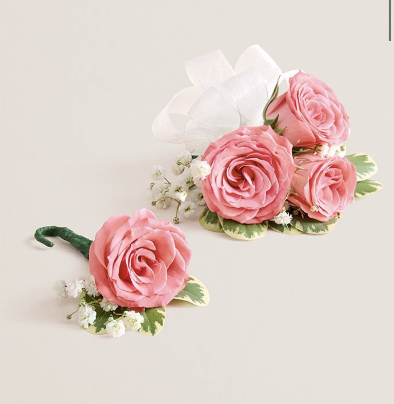 Light Pink Corsage &amp; Boutonniere Set (White Bow) - This striking corsage and boutonniere set, featuring delicate light pink blooms, is thoughtfully designed to pair perfectly, creating a polished and harmonious look for any special occasion. Each piece showcases carefully selected light pink flowers and accents, offering a vibrant and refined touch that complements your ensemble beautifully.