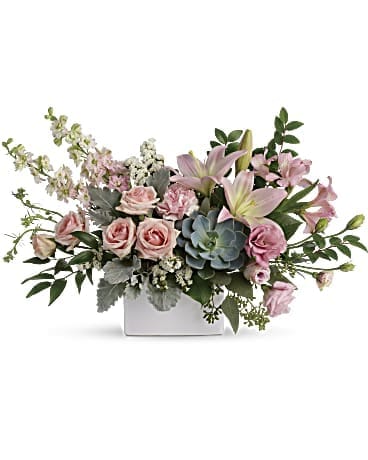 Low arrangement of pink roses, lilies, and a central succulent in a white rectangular vase