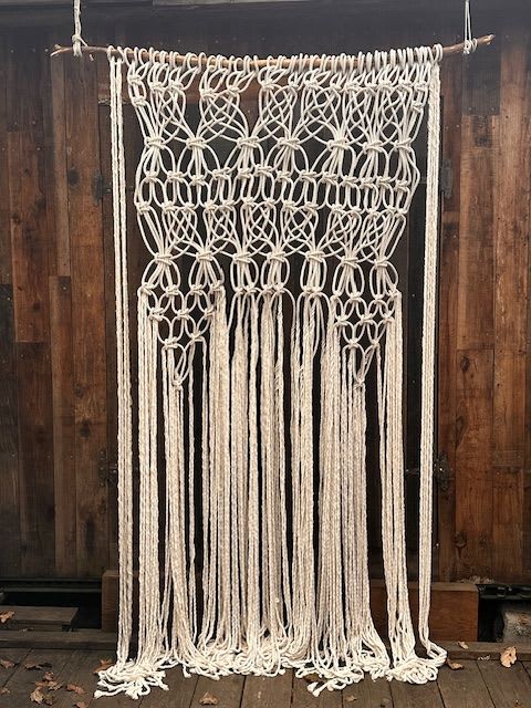 Macrame Wall Hanging  - Hand Crafted - One of a kind piece.  Stunning, oversized macramé wall hanging, handcrafted with meticulous detail and artistry. Measuring an impressive 9 feet tall by 5 feet wide, this piece serves as a dramatic centerpiece for large spaces—perfect for accenting living room walls, wedding backdrops, event spaces, or studio interiors.  Woven from quality, cotton ivory macrame cord in an exquisite pattern, the design combines intricate knotwork, cascading fringe, and layered textures that create depth and movement.   Mounted on a wooden branch, this piece celebrates craftsmanship and nature’s simplicity while commanding attention with its scale and symmetry. 