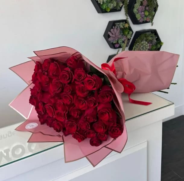 50 Red Roses Bouquet - Quantity: STANDARD - 50 roses DELUXE - 75 roses PREMIUM - 100 roses  A Bouquet of 50 premium long stem red roses in wrapping. Bold, passionate, and unforgettable — our 50 Red Roses Bouquet is the ultimate symbol of love and devotion. Handcrafted with premium long-stem roses, each bloom is carefully arranged and wrapped in elegant pastel paper with a satin ribbon for a timeless finish. This bouquet is designed to make a powerful statement, perfect for the most meaningful moments in life.    •    50 premium long-stem red roses     •    Wrapped in stylish pastel paper with satin ribbon     •    Represents deep love, passion, and commitment     •    Perfect for anniversaries, proposals, Valentine’s Day, or milestone celebrations  VASE NOT INCLUDED