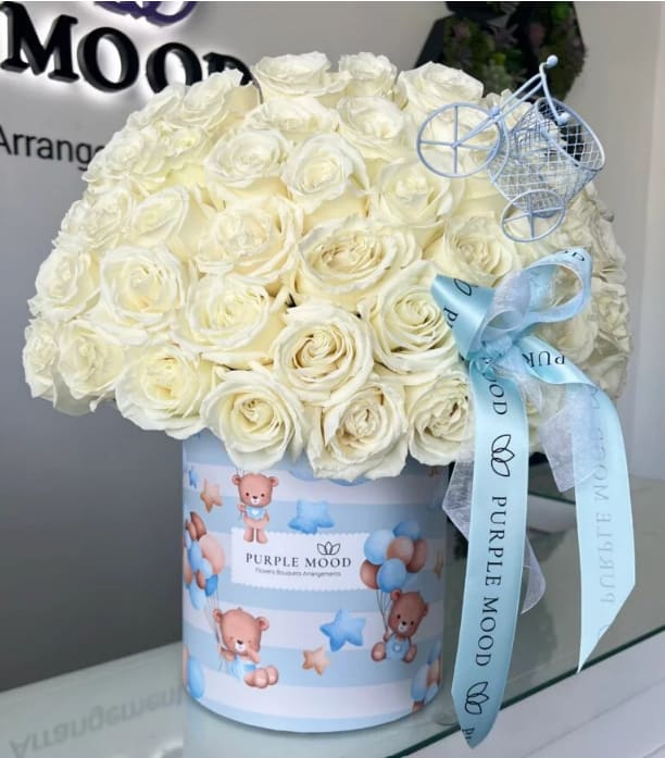 50 White Roses For Baby Boy - Container size D8.25'x H9.5'  White roses in a  butterfly box. Celebrate new beginnings with our 50 White Roses for Baby Boy arrangement. Pure white roses are carefully arranged in a baby-blue themed hatbox adorned with teddy bears and balloons, symbolizing innocence, purity, and joy. Finished with a satin ribbon, this arrangement is the perfect way to congratulate proud parents and welcome their little one into the world.   •    50 premium white roses arranged in a baby-themed hatbox     •    Elegant dome design finished with satin ribbon     •    Symbolizes purity, joy, and new beginnings     •    Perfect gift for congratulating new parents and welcoming a baby boy