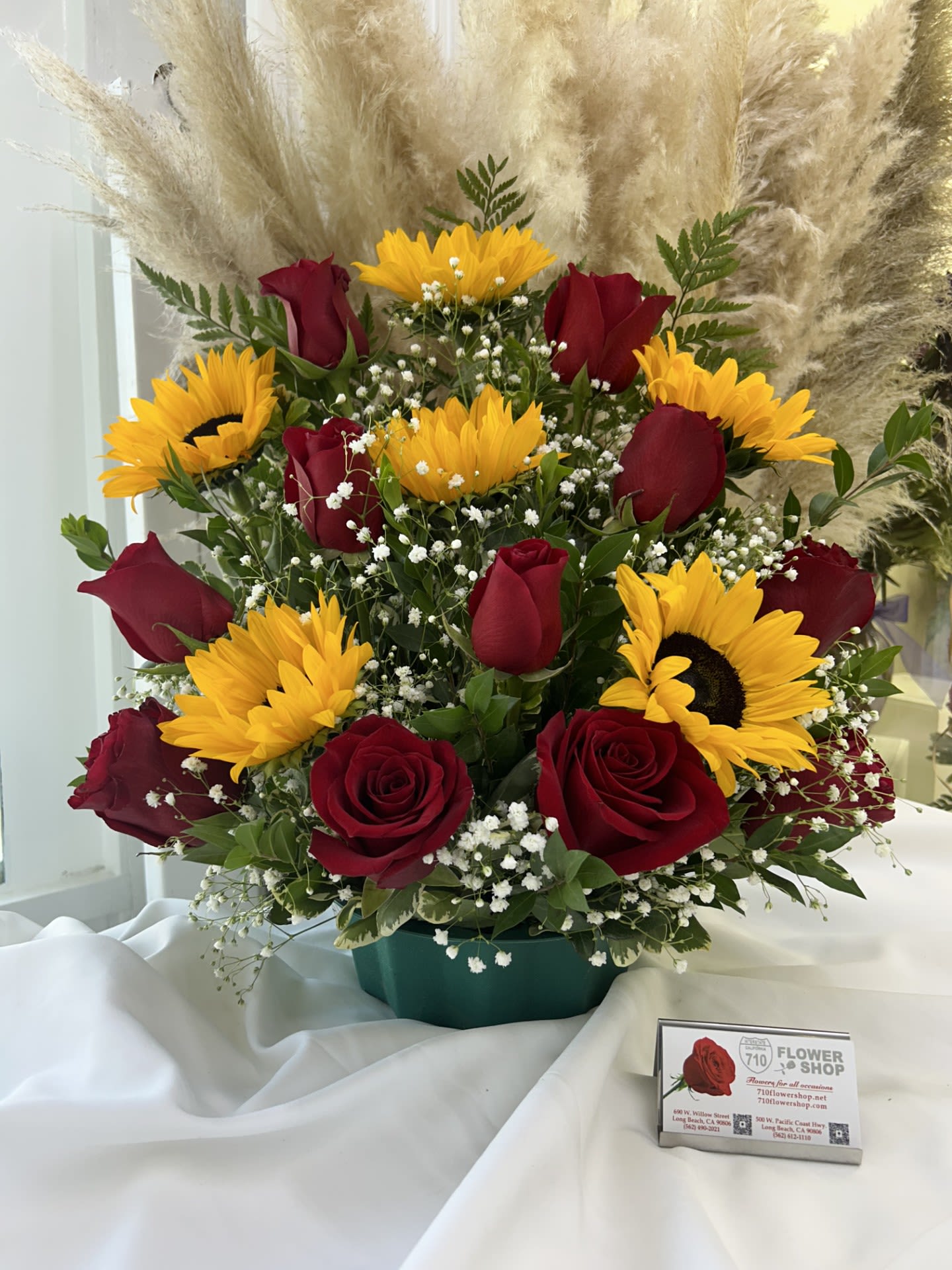 Sunset Romance - The rich red roses paired with the bright yellow sunflowers create a beautiful contrast that feels both passionate and warm, like a sunset If some flowers and/or the vase are not available there will be minor substitutions.