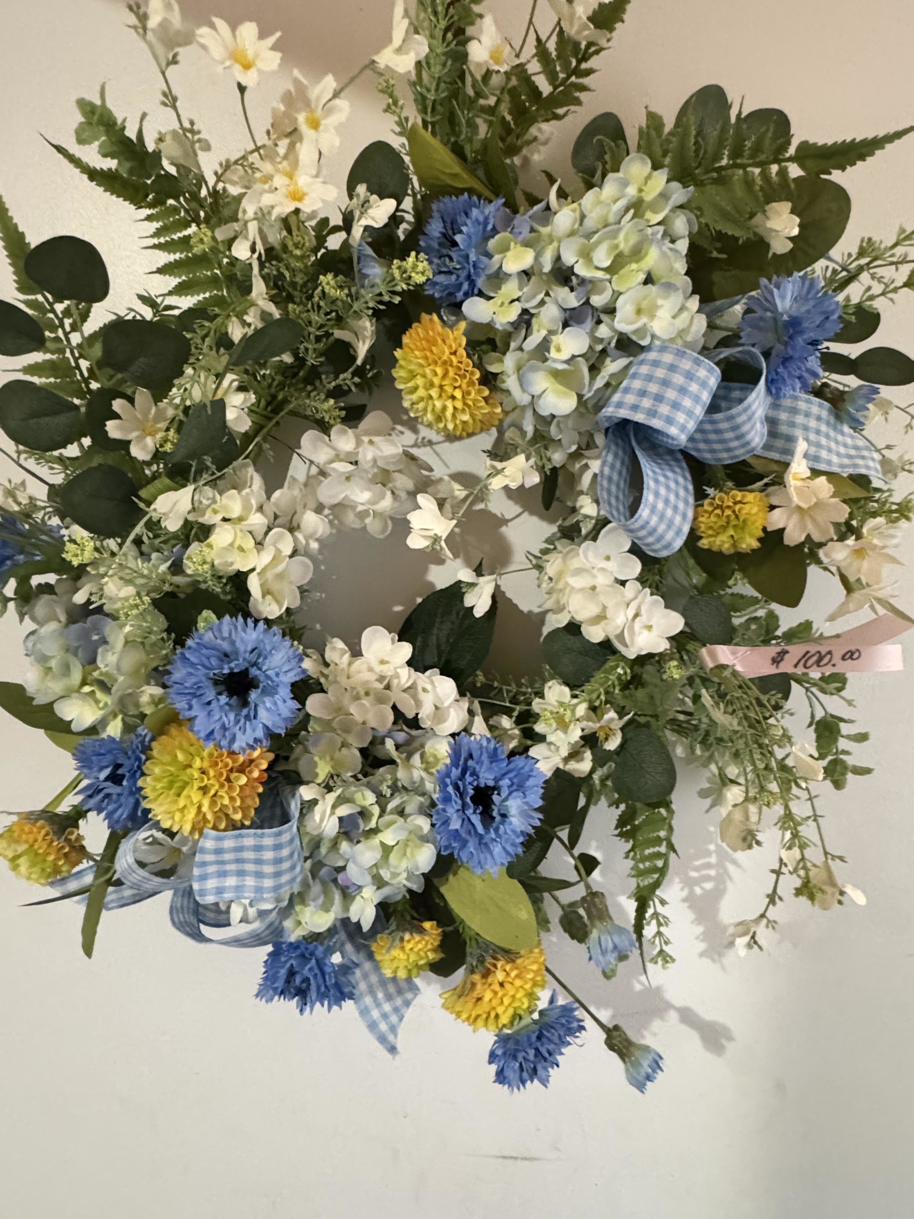 BLUE SKY PICNIC (PERMANENT WREATH) - A permanent wreath with white and yellow faux blooms and decorated with blue checkered ribbon