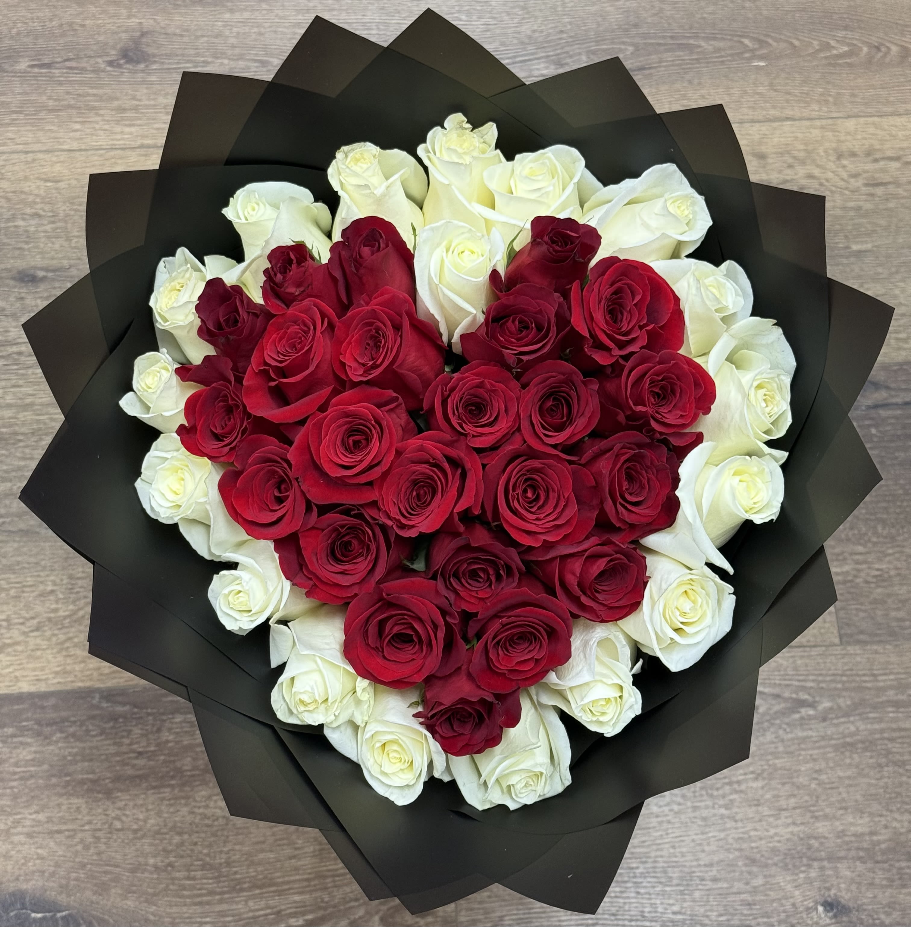 Midnight Heart Bouquet - The Midnight Heart features red roses arranged in a central heart shape, surrounded by a border of white roses. This arrangement is finished with a matte black Korean paper wrap.