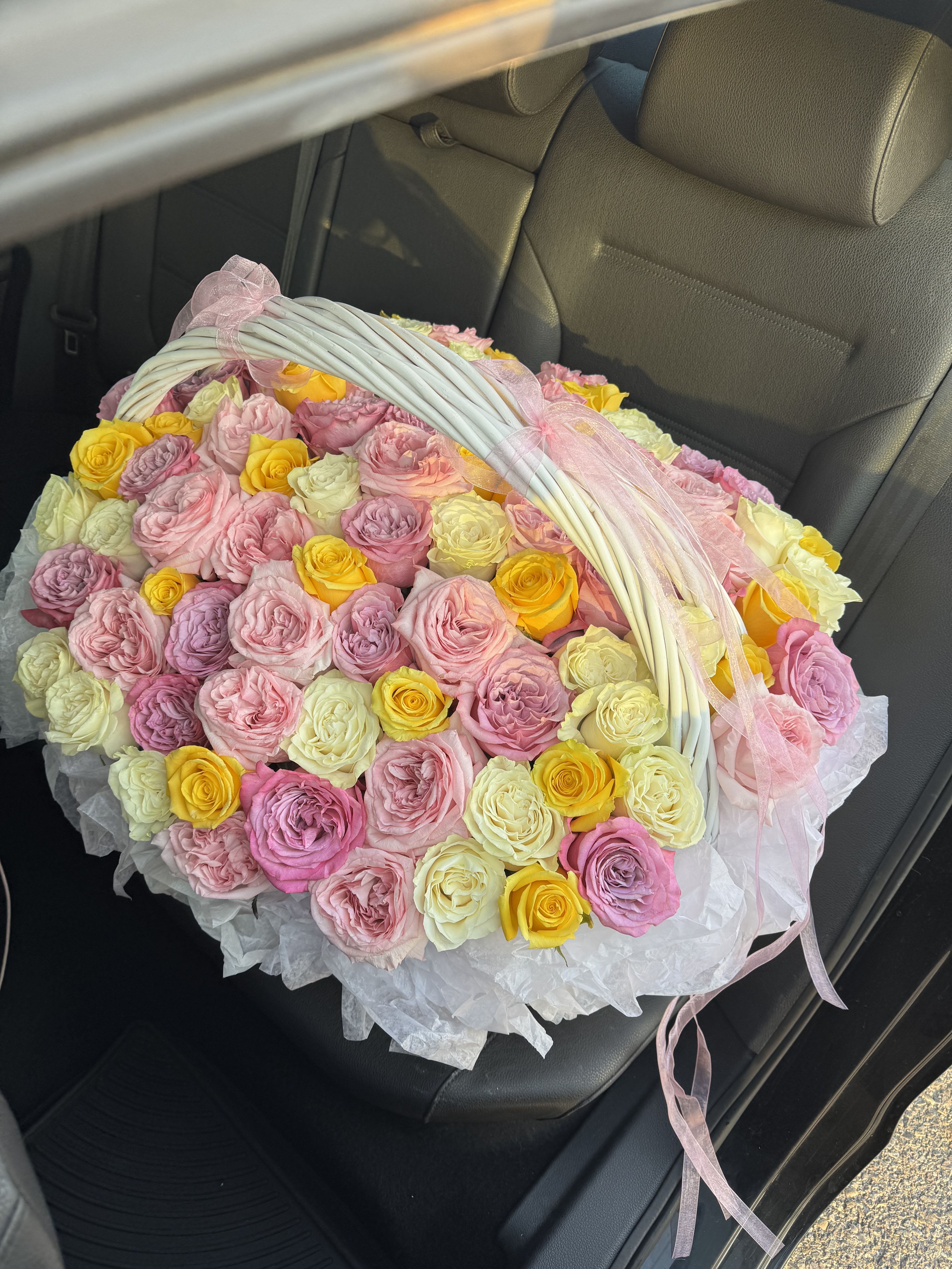  ⸻  A Basket of 100 Roses in Four Stunning Varieties - There are few gifts in the world that can rival the timeless elegance of roses. Their beauty, fragrance, and symbolism have made them one of the most beloved flowers for centuries. Imagine the delight of receiving not just a bouquet, but a grand basket filled with 100 roses, carefully selected from four different varieties, each chosen for its charm and meaning. This extraordinary arrangement brings together roses in shades of purple, pink, yellow, and white, creating a masterpiece of color and emotion.  The purple roses in the basket add a touch of mystery and enchantment. Often associated with admiration, elegance, and love at first sight, they bring depth and sophistication to the entire arrangement. Their unique hue stands out, offering a modern yet regal charm.  The pink roses symbolize tenderness, romance, and admiration. They are soft and graceful, perfectly complementing the deeper tones of purple. Their gentle blush conveys emotions of gratitude and sweetness, making them a universal favorite for any occasion.  The yellow roses bring sunshine into the basket. Bright, cheerful, and full of joy, they symbolize friendship, happiness, and new beginnings. Their vibrant shade uplifts the spirit and adds a warm glow to the composition.  The white roses, classic and pure, complete the ensemble with their timeless beauty. They symbolize innocence, sincerity, and new journeys, balancing the vivid colors with a sense of peace and harmony.
