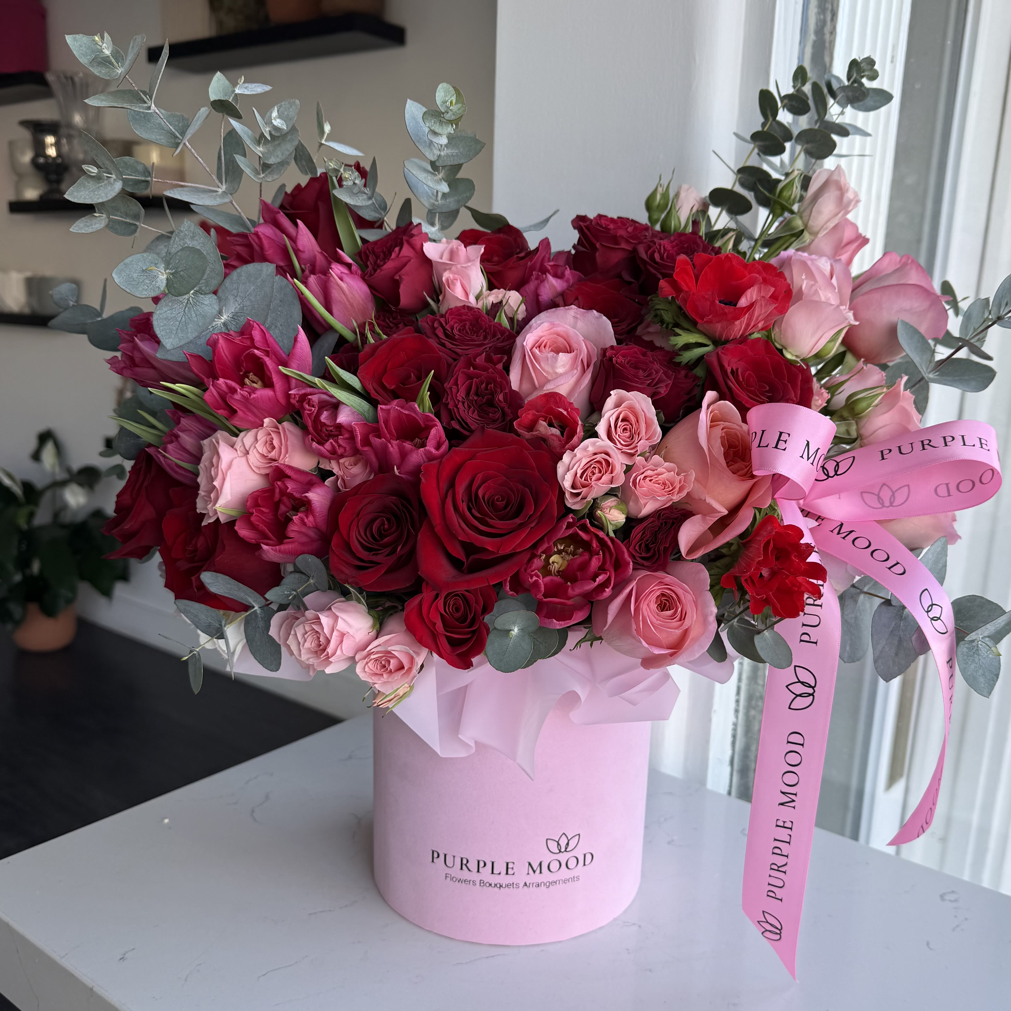 Velour Rosé Box - Velour Rosé Box is a luxurious floral arrangement featuring premium roses in deep red and soft blush tones, accented with seasonal blooms and fresh eucalyptus. Designed in our signature pink hat box and finished with a silk Purple Mood ribbon, this composition feels rich, soft, and intentionally elegant — like velvet in floral form.  Perfect for Valentine’s Day, anniversaries, or refined romantic gestures, Velour Rosé Box delivers timeless beauty with a modern, boutique aesthetic.  Details: 	•	Premium red &amp; blush roses 	•	Seasonal accent florals 	•	Fresh eucalyptus greenery 	•	Signature Purple Mood hat box 	•	Silk ribbon finish