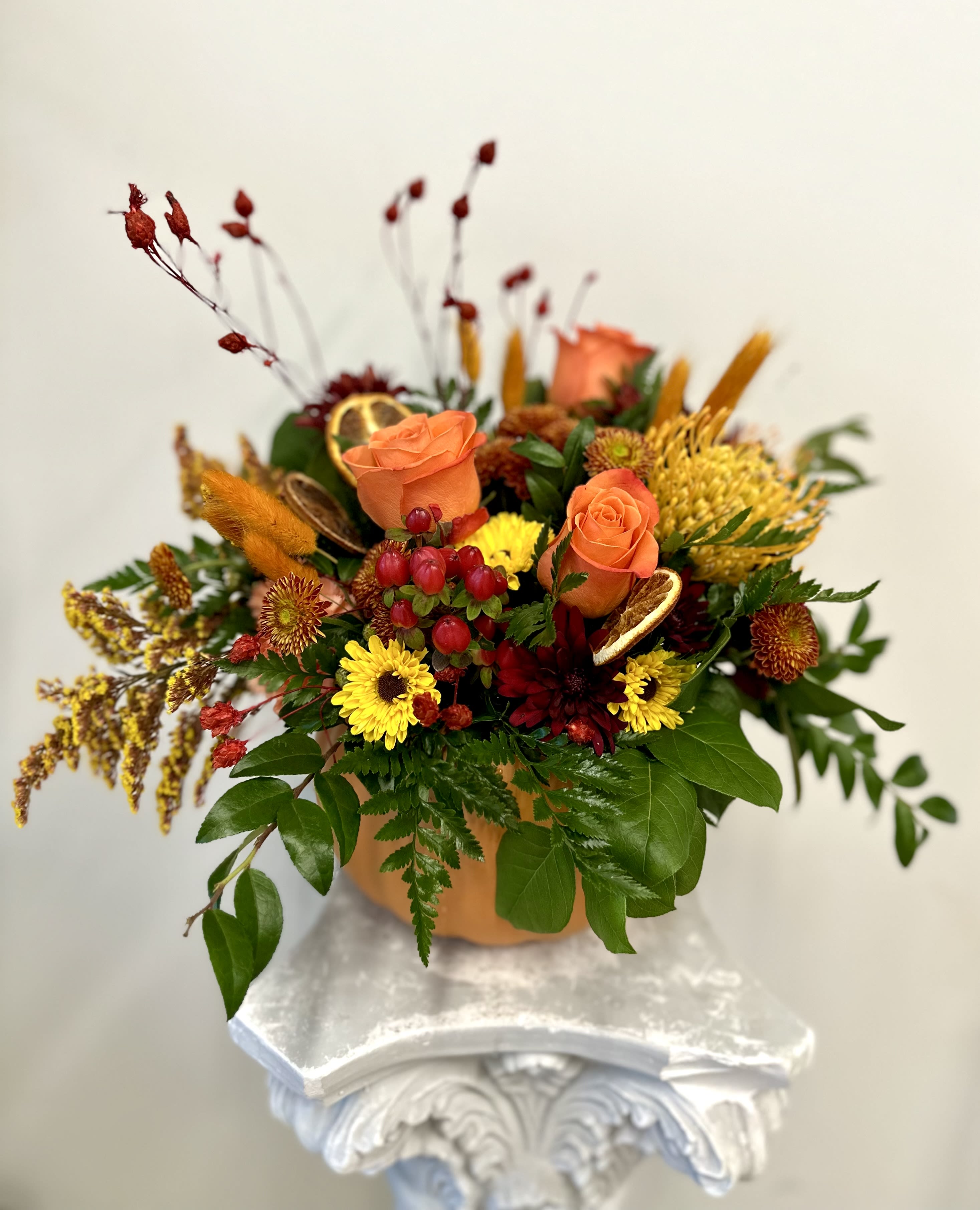 Harvest Pumpkin By Westford Florist Art by Veny - Elevate your seasonal decor with the Harvest Pumpkin by Westford Florist Art by Veny. This exquisite arrangement showcases a beautiful range of autumnal blooms, meticulously curated to bring warmth and vibrancy into your home. Rich hues of oranges, deep reds, and golden yellows blend harmoniously with textured foliage, creating a stunning centerpiece that captures the essence of fall. Perfect for tables, sideboards, or mantles, this elegant display not only enhances your space but also invites the cozy spirit of autumn into every gathering. Embrace the beauty of the season with a touch of sophistication and charm.