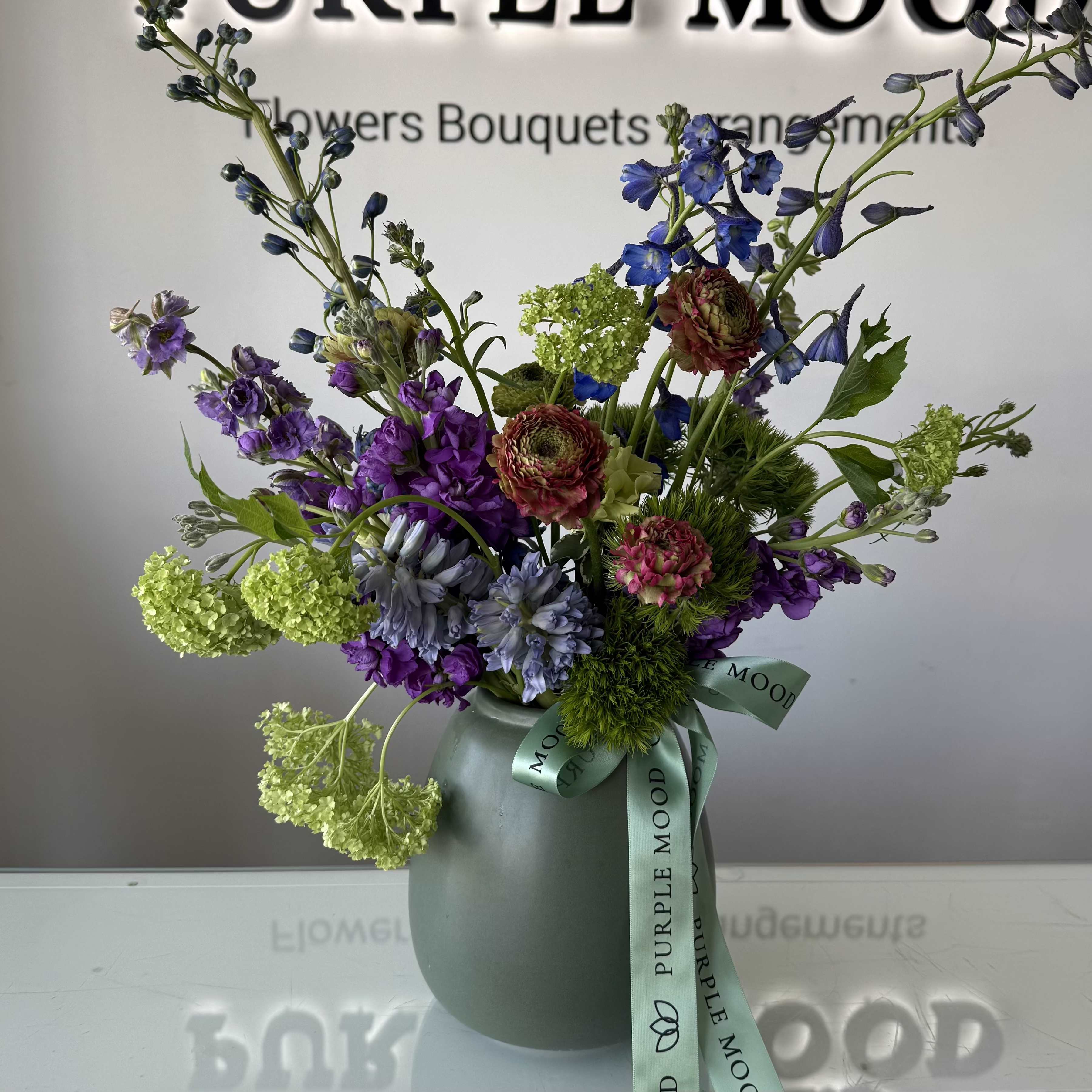 Breeze Vase - An airy garden-style arrangement featuring seasonal blooms in soft purples, fresh greens, and delicate textures. Designed with natural movement and elegance, Breeze Vase brings the feeling of a gentle spring breeze into any space. Vase included.