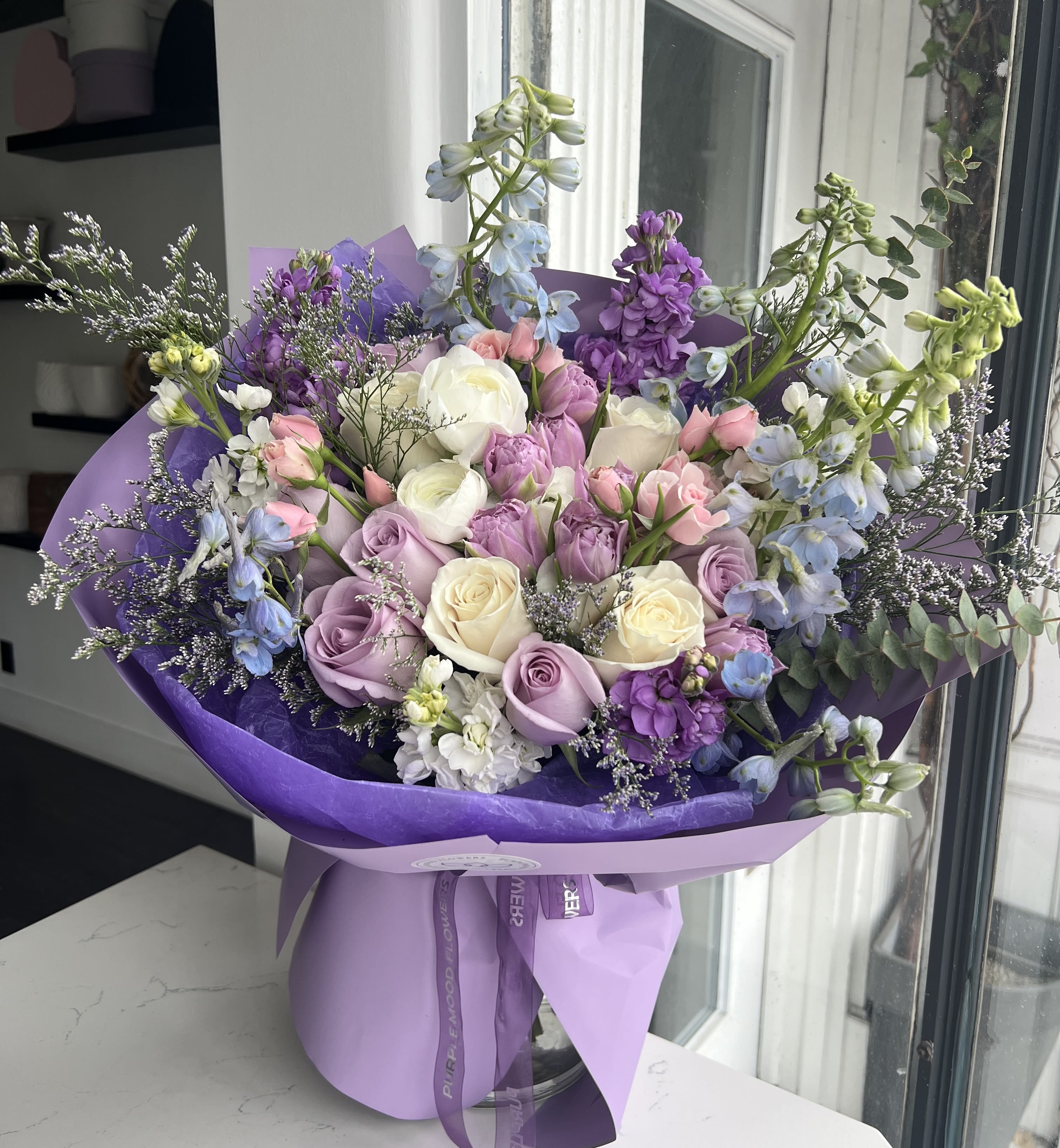 First Impression Bouquet - Make a lasting statement with the First Impression Bouquet — a vibrant and enchanting mix of blooms in soft pastels and lively hues. Designed to capture hearts at first glance, this arrangement radiates elegance and charm, making it perfect for birthdays, anniversaries, or simply brightening someone’s day.   •    Handcrafted bouquet with a mix of roses, lisianthus, delphinium, and seasonal accents     •    Color palette: lavender, cream, blush pink, and fresh green     •    Available in three sizes: Standard, Deluxe, and Premium     •    Wrapped in premium lilac paper with a satin ribbon finish     •    Ideal for gifting when you want to leave a beautiful first impression  VASE NOT INCLUDED