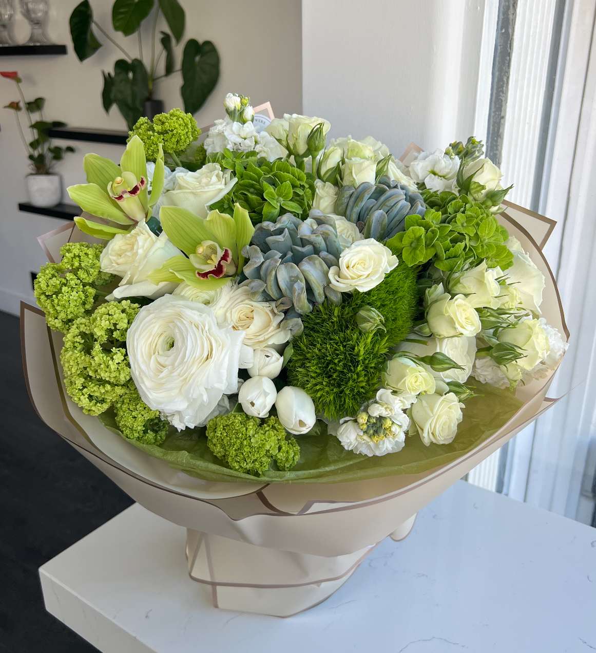 Garden Bouquet -  Bring the freshness of a blooming garden indoors with this elegant hand-tied bouquet. A lush mix of ivory blooms, vivid greens, and textured succulents creates a chic yet natural look. Perfect for birthdays, celebrations, or simply brightening up any space with timeless beauty.  Key Features:     •    Fresh mix of premium white roses, orchids, and seasonal greens     •    Highlighted with succulents and playful textures for a modern twist     •    Wrapped in stylish neutral paper for a polished finish     •    A sophisticated choice for any occasion, blending elegance with nature’s charm