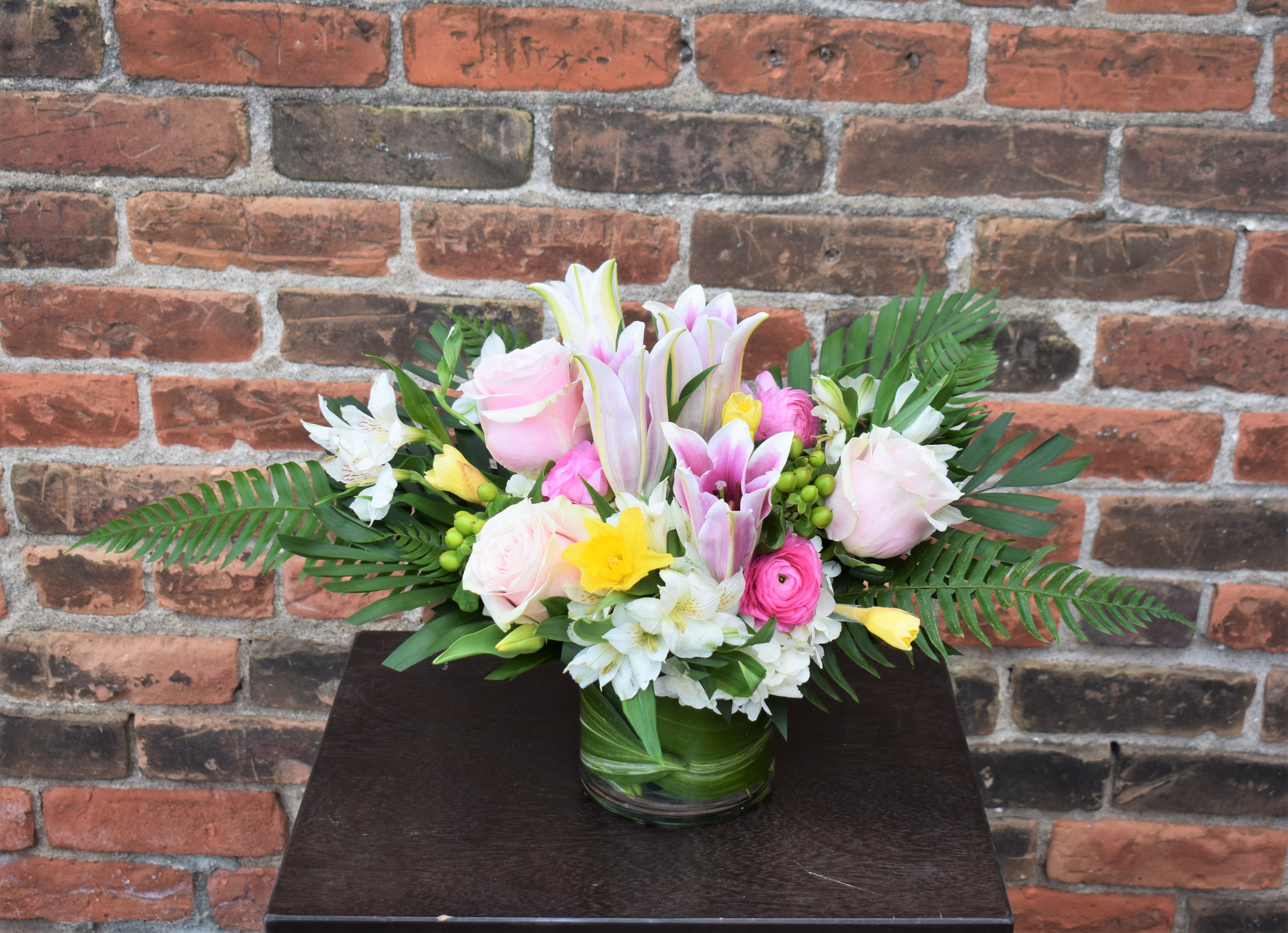 Celebrate Spring - The best of spring! tulips, lilies, daffodils, hydrangea, roses, hypericum, roses, and ranunculus are arranged in a vase and accented by spring greens. These soft pink and yellow blooms create a full, elegant bouquet, perfect for celebrating the season! 