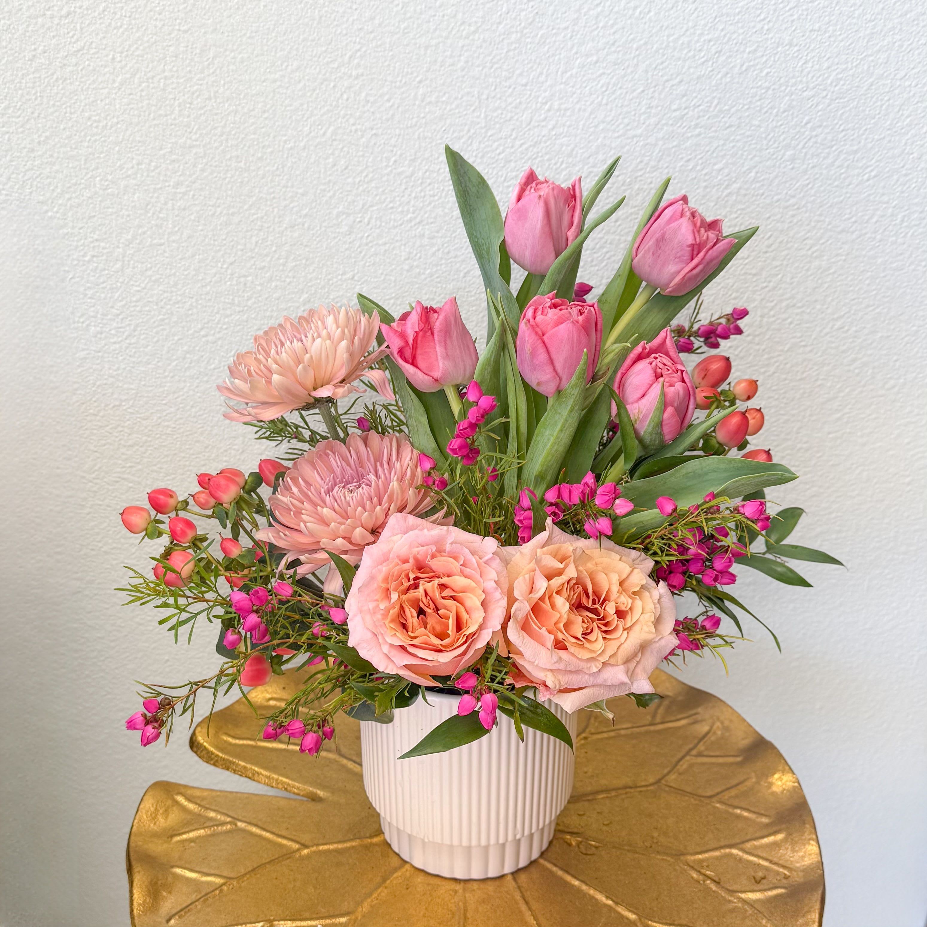 Spring Fling - If you're looking for something special this spring. This is it! But like any spring fling, it won't be around for long. The highlight of this arrangement are fragrant, tiny, hot pink blooms called Boronia. Paired with pink double tulips, peach roses, coral hypericum and dreamy beige mums this arrangement has all the oohs and ahhs of the brief blooms of spring.