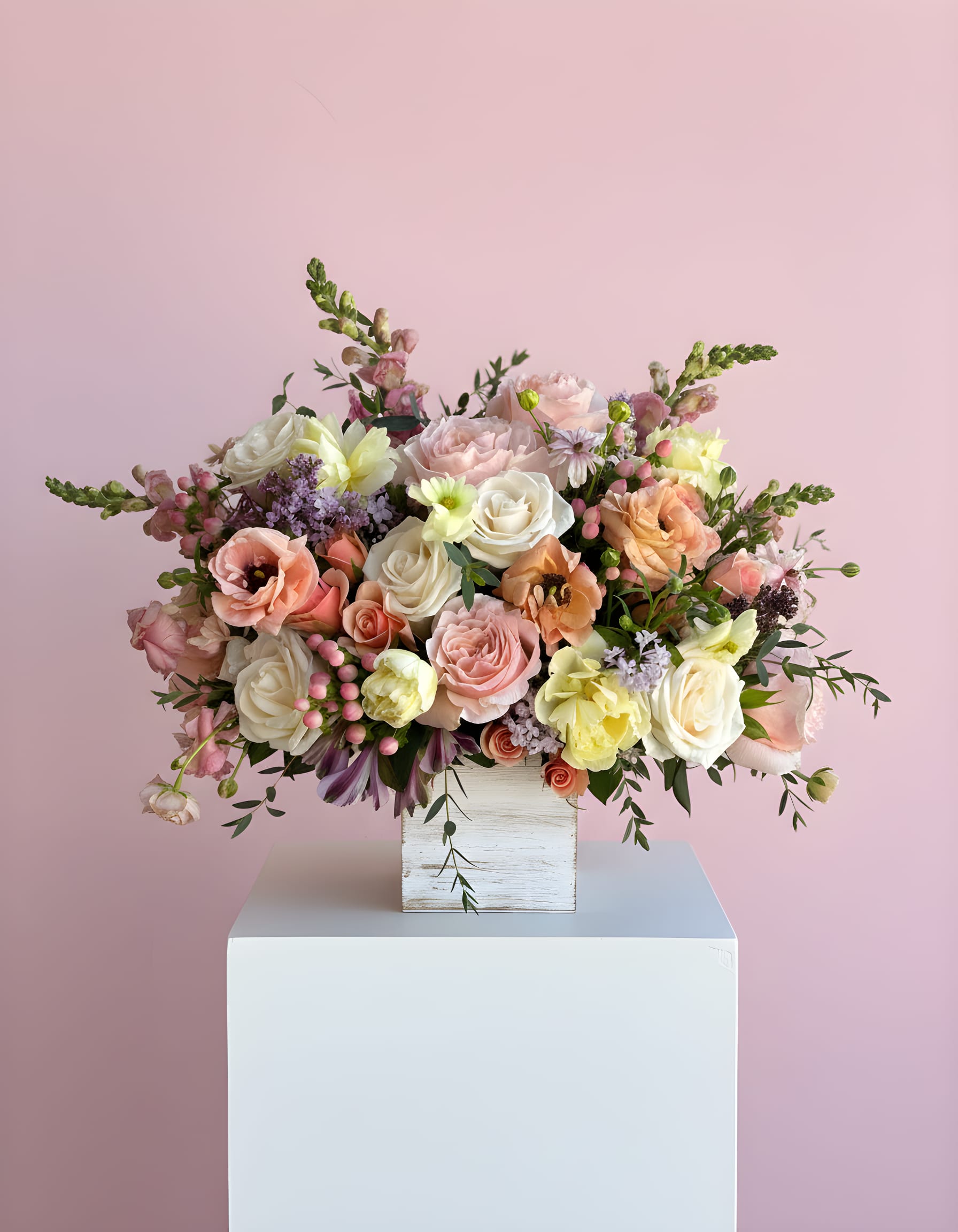 Romantic Garden  - This arrangement has a soft, romantic garden style with a color palette that has delicate pinks, peach, lavenders and whites. It’s designed all the way around in a low rectangular wooden box, giving it a natural, slightly rustic foundation while still feeling refined.