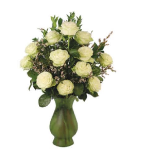 DAY IN THE PARK - A generous cluster of pale yellow roses - gathered into a soft, rounded bouquet - creates a calm, luminous presence perfect for an anniversary, birthday, sympathy arrangement, or simply to say "I'm thinking of you." The pale cream-to-soft-yellow petals read as warm and uplifting, while delicate pink filler blooms and fresh green accents give texture and a gentle, romantic contrast that makes the recipient feel quietly celebrated.  Set in a curvy White glass vase, the composition balances traditional elegance with a slightly modern touch; the vase's deeper green grounds the airy roses and highlights the arrangement's soft color palette of yellow, green, white, and pink. Each hand-tied design features a dozen or more roses arranged upright for a full, rounded silhouette - an easy-care gift that arrives ready to display and brings a tranquil, refined charm to a bedside table, mantel, or office desk.