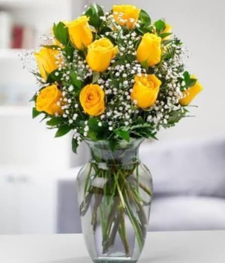 "Sunlit Grace Roses" - Bright yellow roses take center stage in this sunlit birthday bouquet, sympathy arrangement alternative, or cheerful get-well gift-an uplifting choice for celebrations, congratulations, or simply to say "I'm thinking of you." The rounded, clustered shape lets the golden blooms read like a single warm gesture; the crisp white filler flowers and fresh green foliage add delicate contrast so the recipient feels genuinely brightened the moment they see it.  A dozen or so yellow roses are gathered with tiny white filler blooms and arranged in a classic clear glass vase that shows the long stems in water, creating a clean, timeless presentation. The compact, slightly flared vase sits comfortably on a table or desk and makes arranging unnecessary-just unwrap and display. Ideal for friends, coworkers, or anyone who could use an encouraging lift, this arrangement arrives ready to enjoy; change the water every few days and trim stems as needed to keep the bouquet looking fresh.